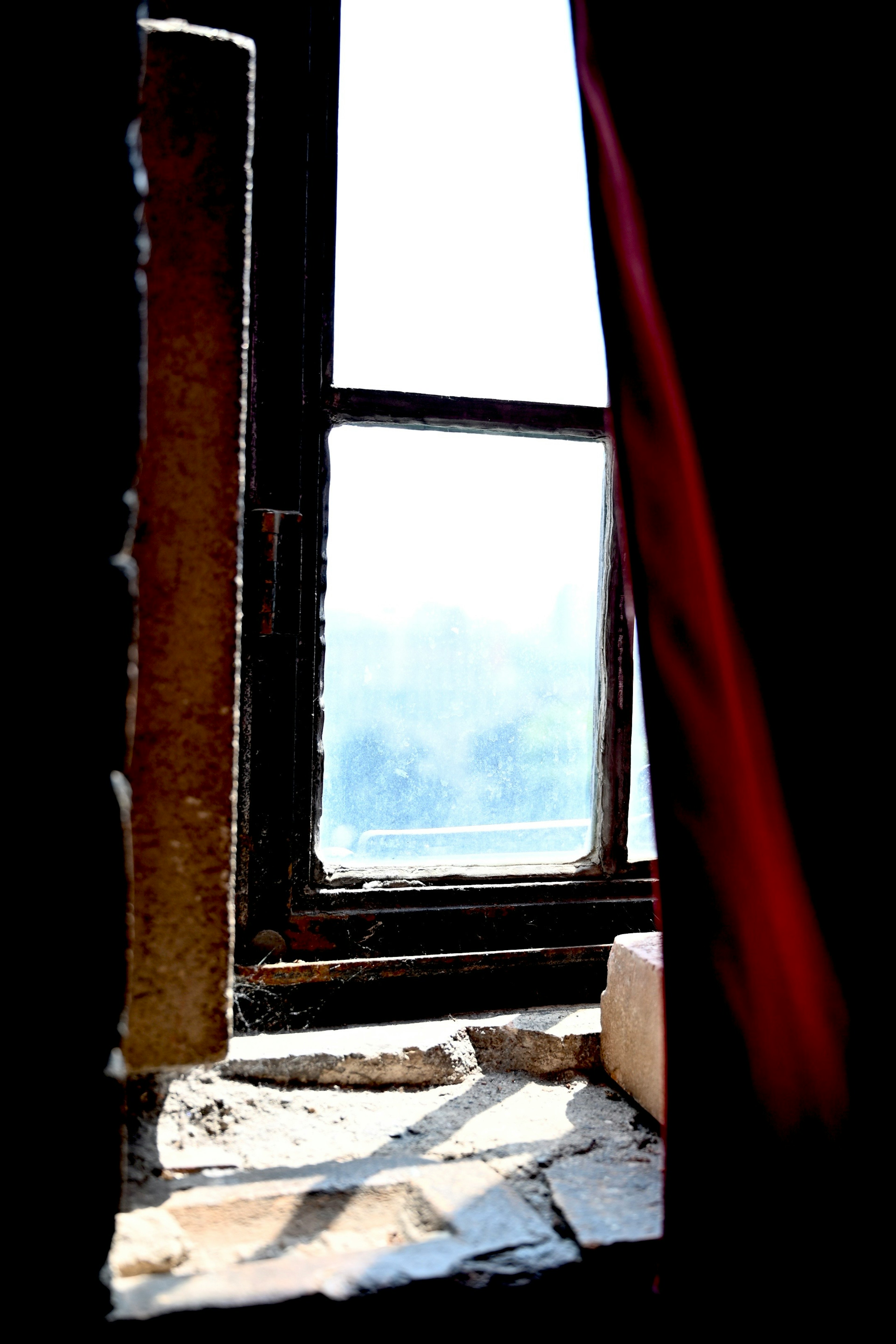 Una vista de una ventana antigua con una cortina roja