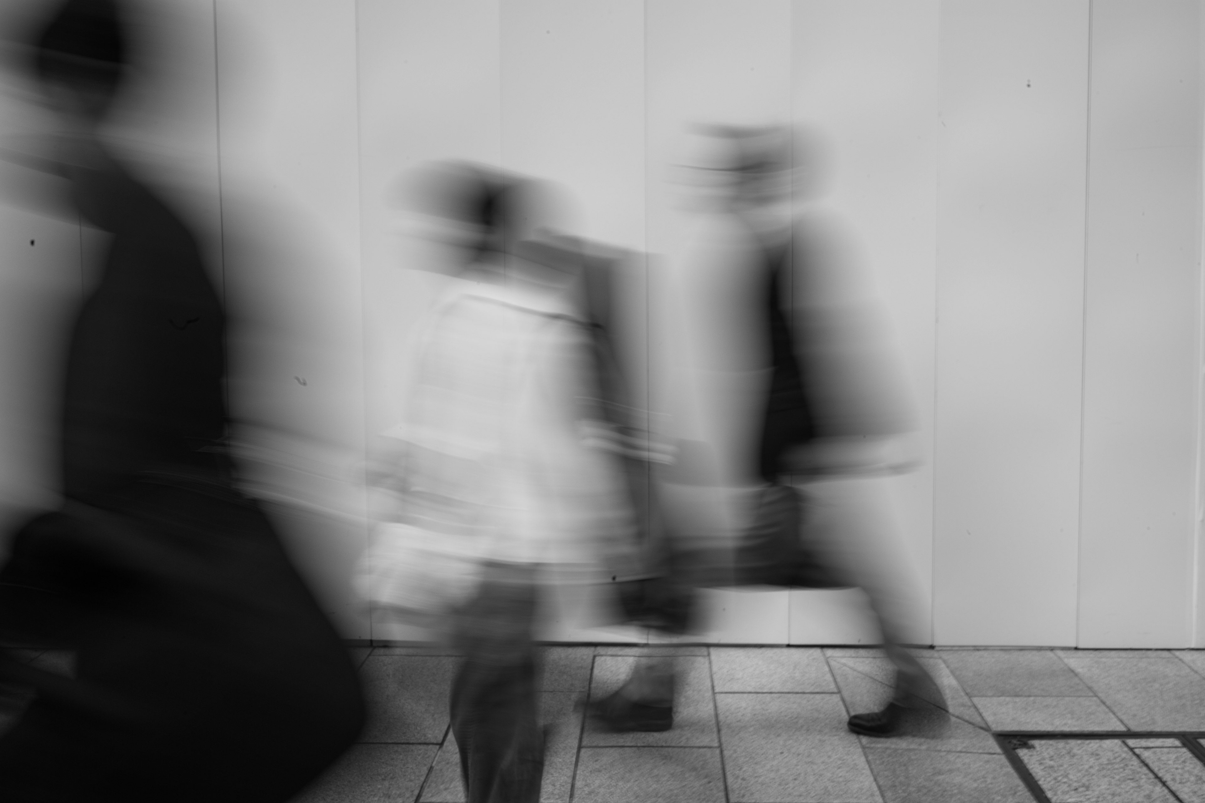 Movimiento borroso de personas caminando en un entorno urbano en blanco y negro