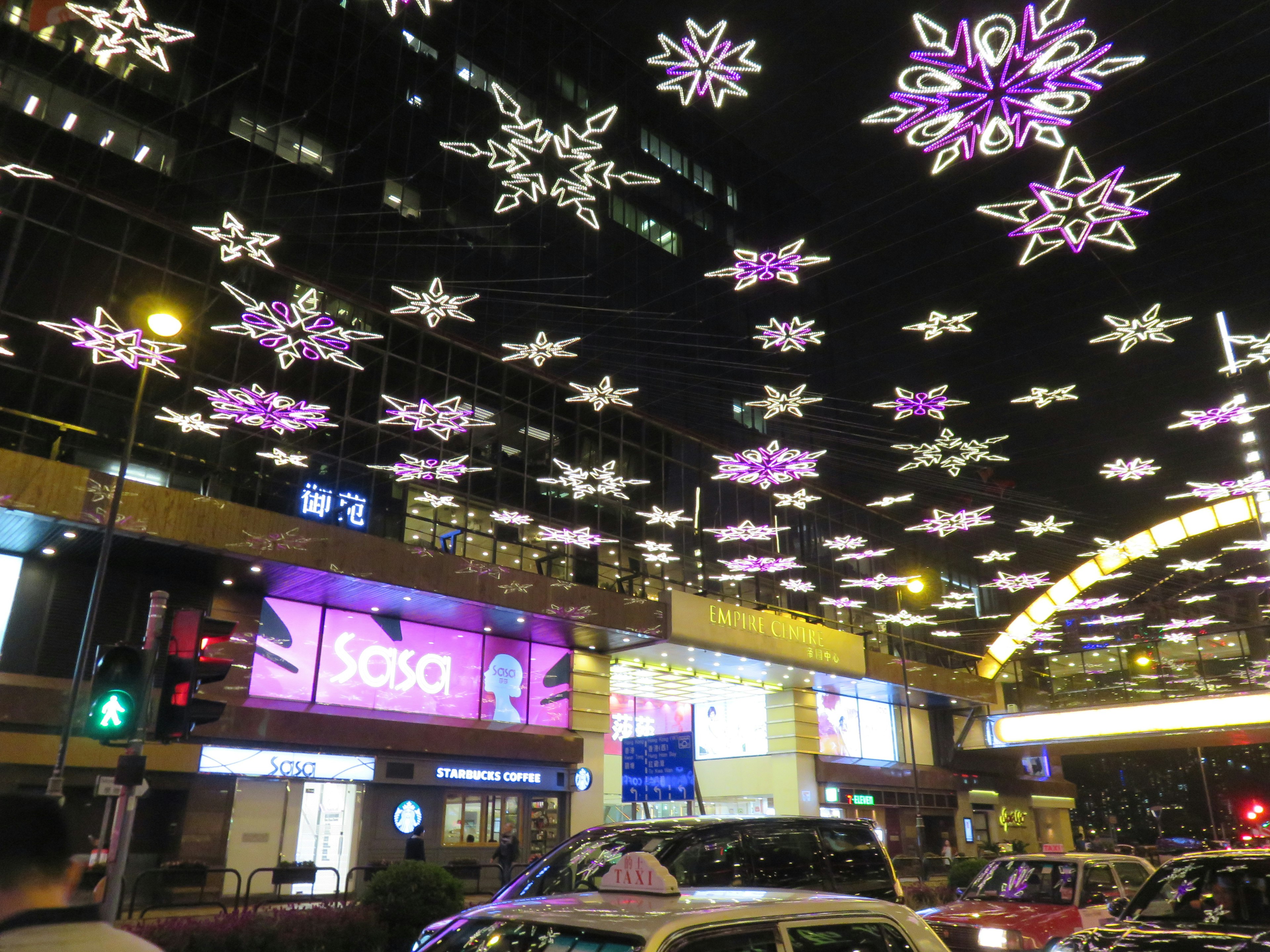 Strada decorata con luci a forma di fiocco di neve viola di notte