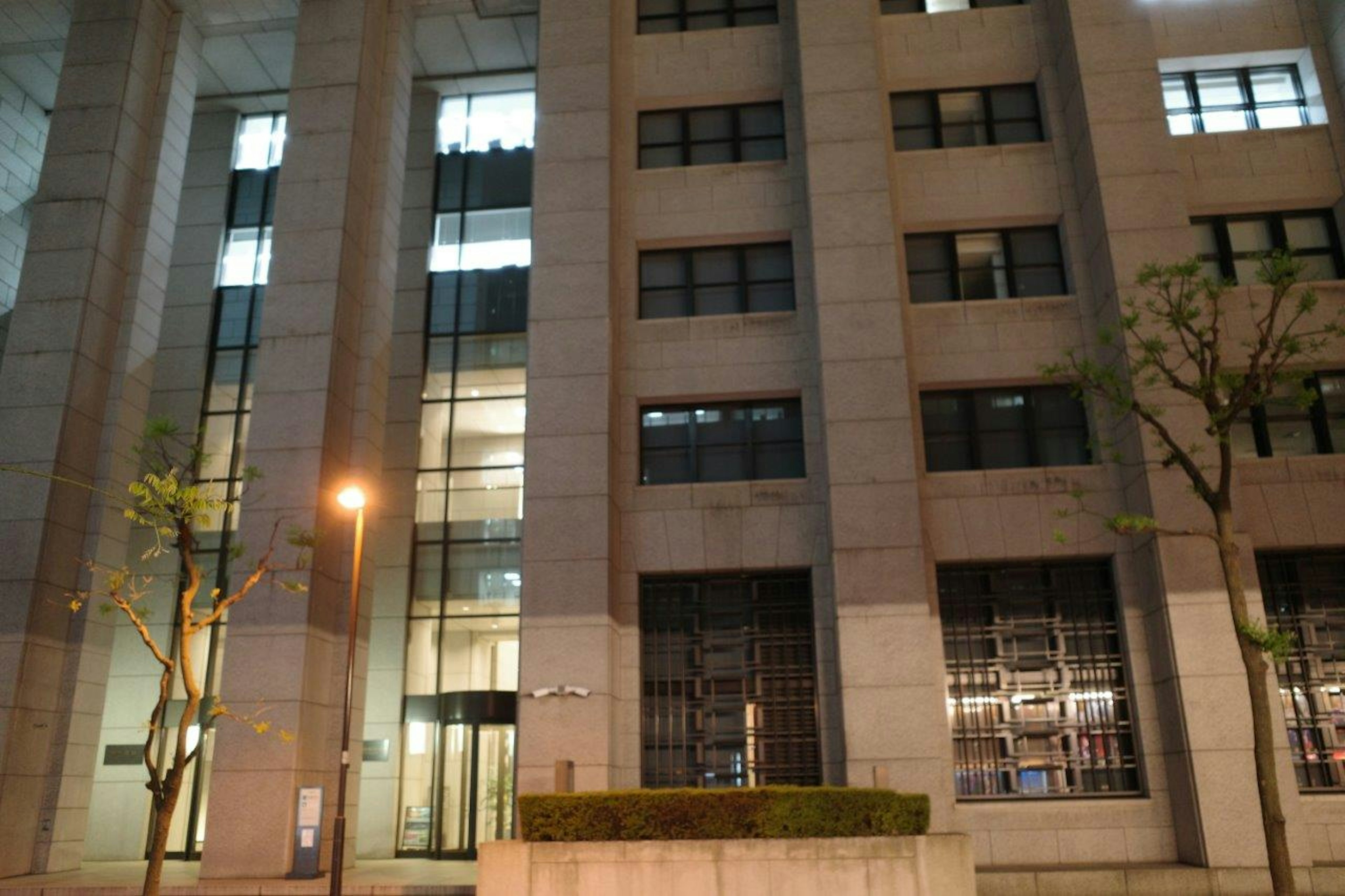 Modern building facade at night featuring illuminated glass and stone elements