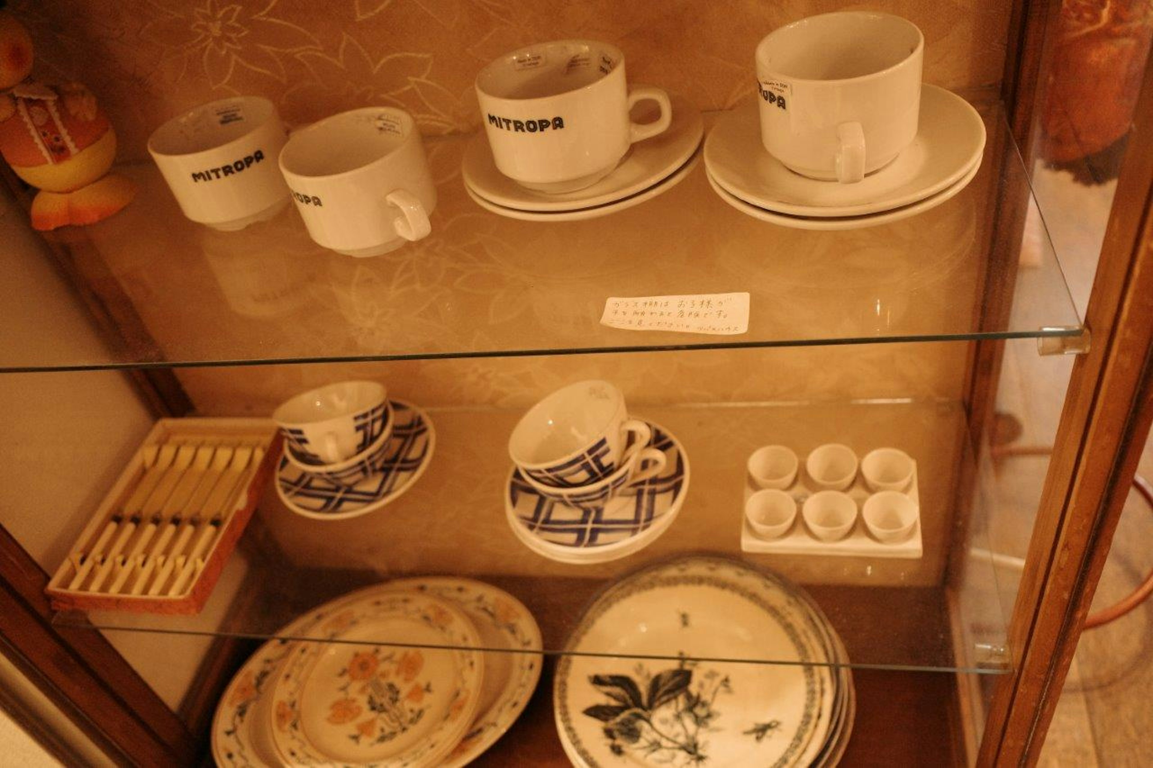 Collection of ceramic cups and plates displayed in a glass case