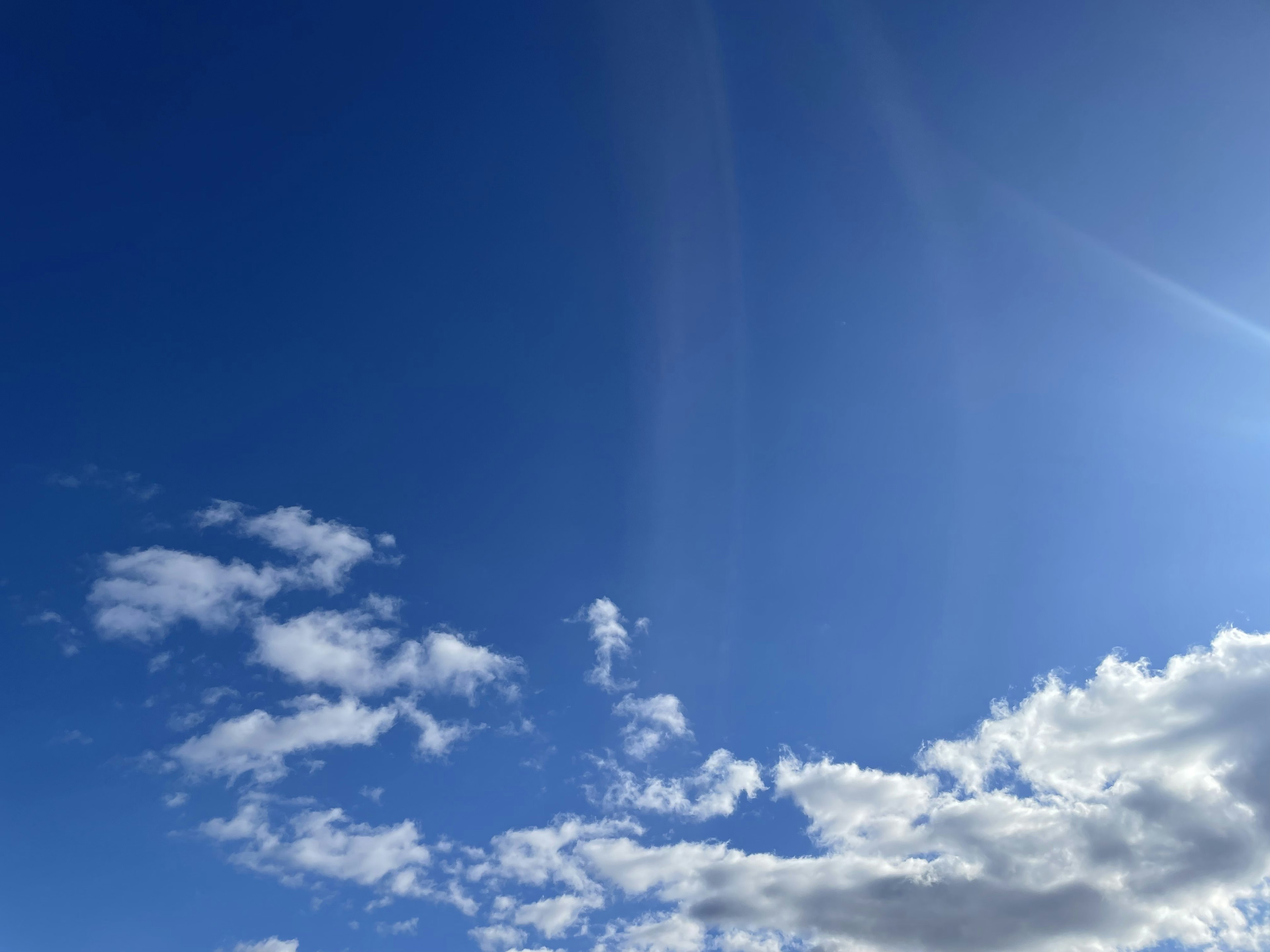 青空に薄い雲と光の筋が見える風景