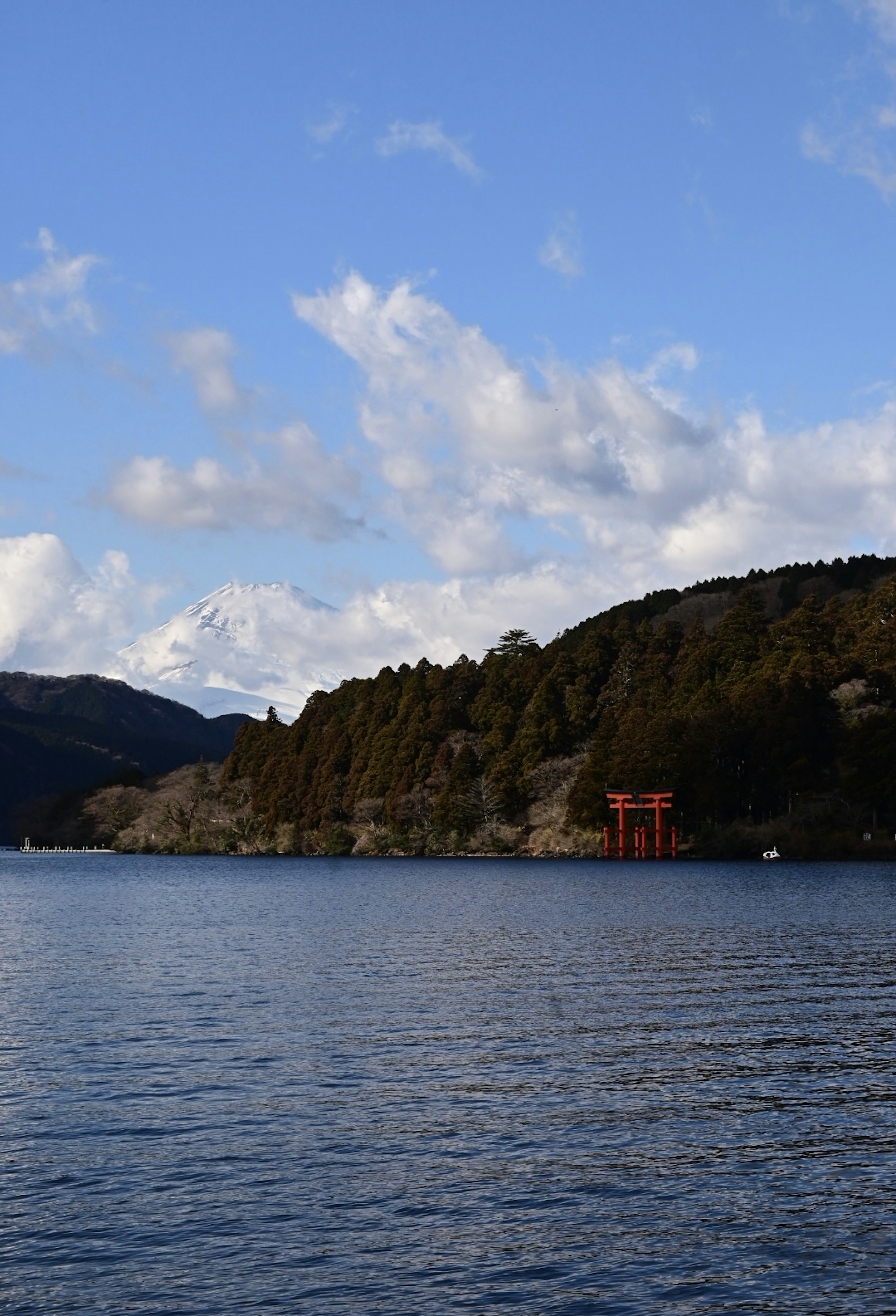 Vue pittoresque du lac avec ciel bleu et nuages mettant en valeur un torii rouge et des collines vertes