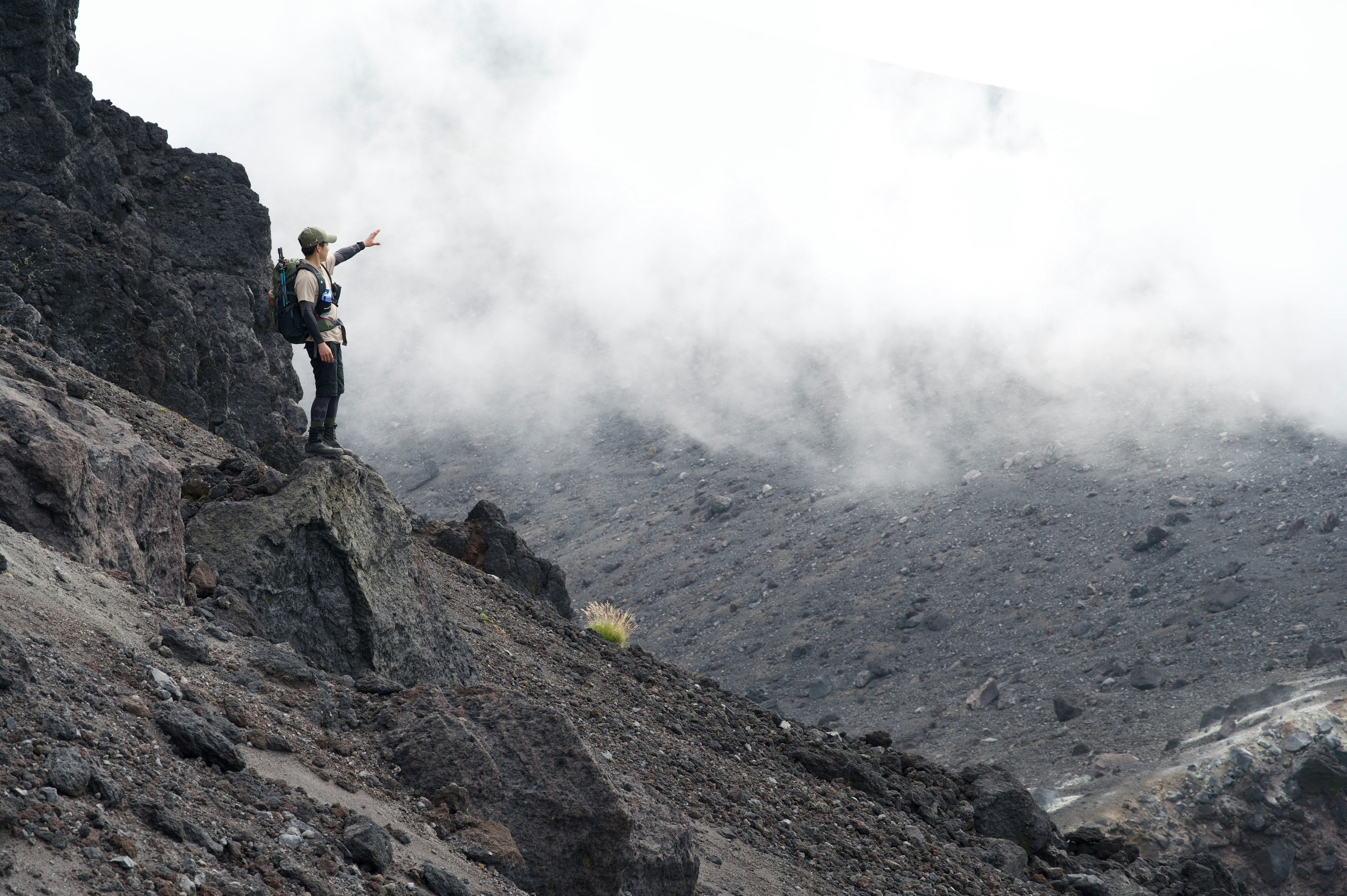 攀登者站在被云雾和岩石地形环绕的火山景观中