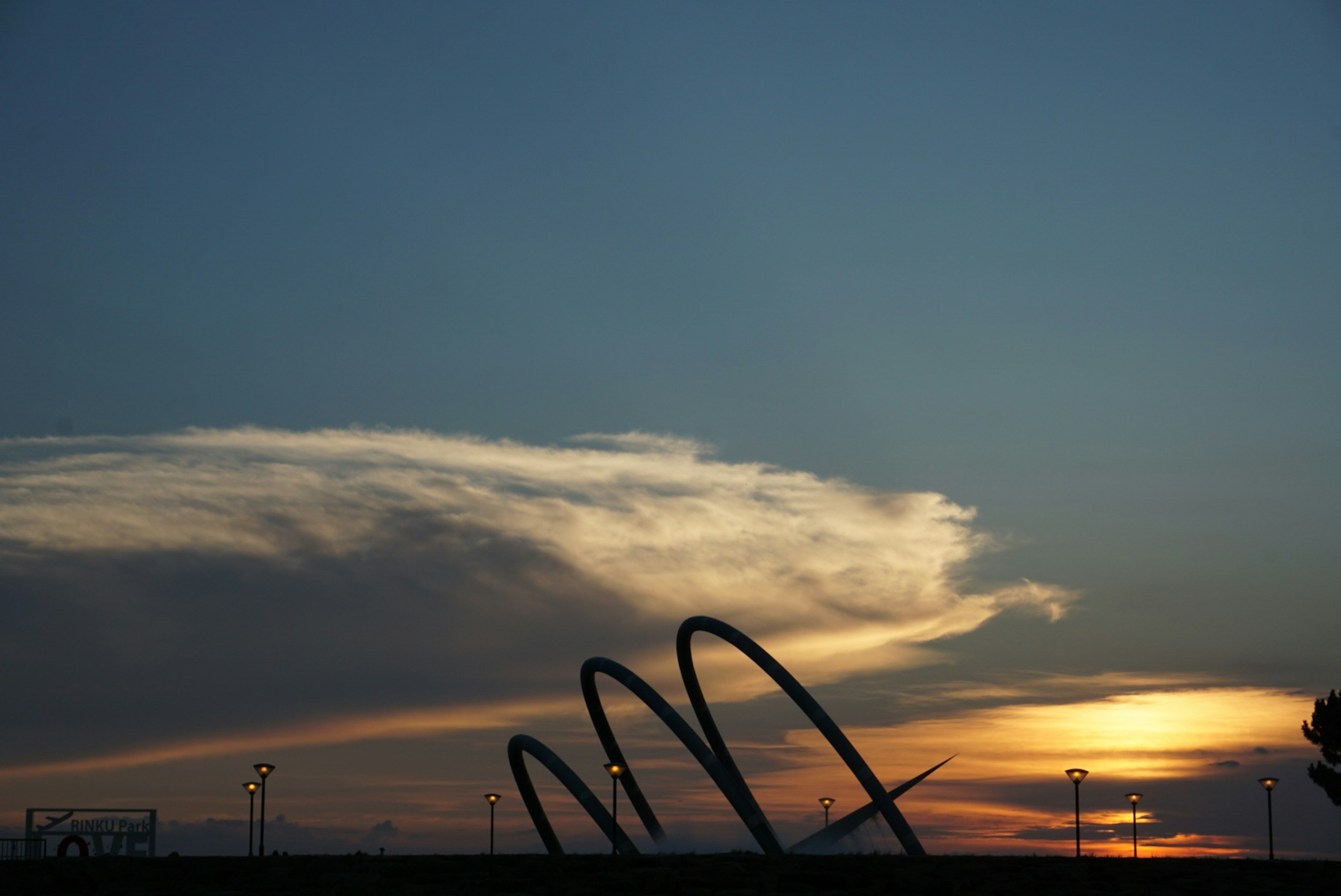 Silhouette einer abstrakten Skulptur vor Sonnenuntergang und Wolken