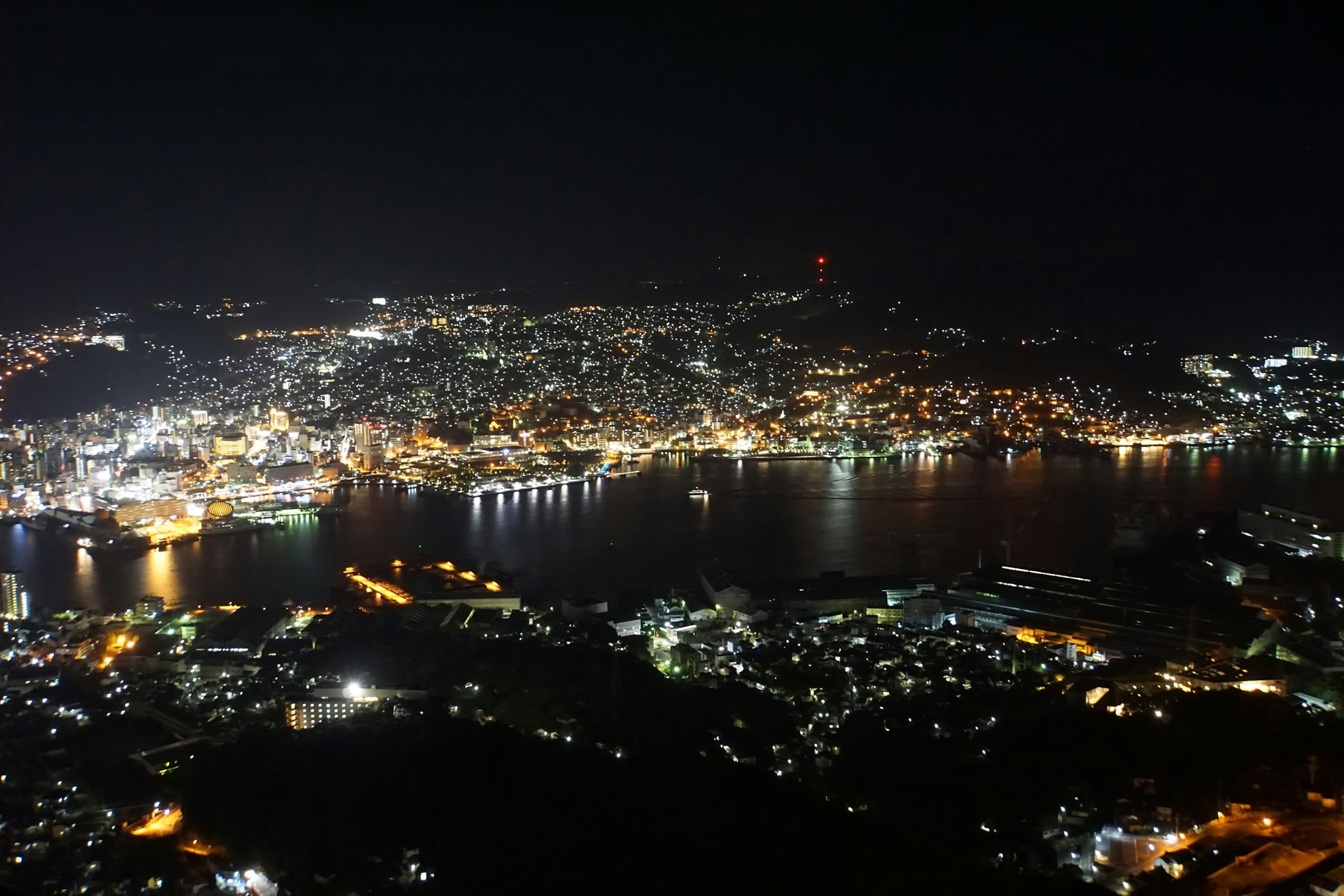 Panoramablick auf die Stadt Nagasaki bei Nacht mit schimmernden Lichtern und Hafen