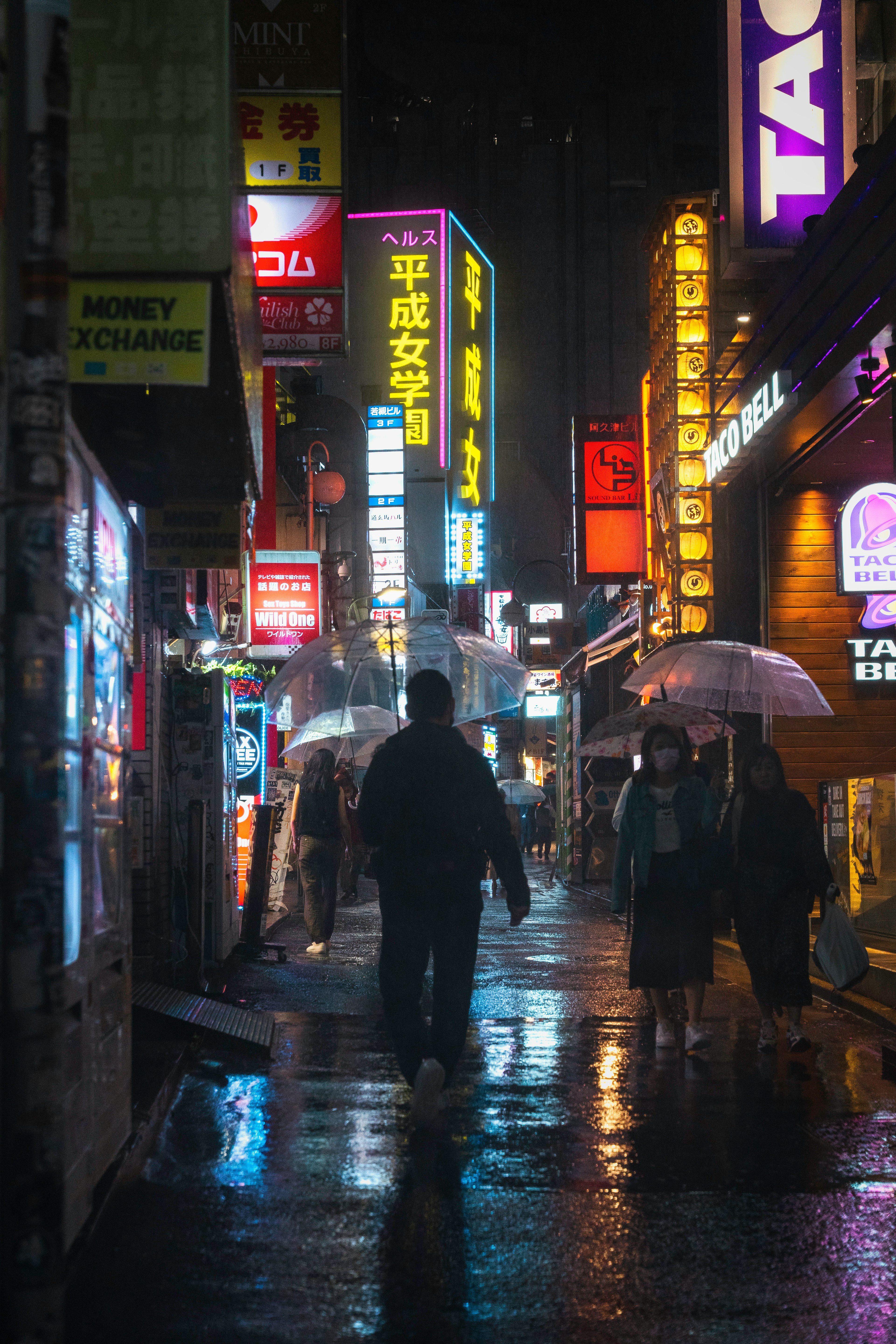 雨の中の街の風景 人々が傘を持って歩いている 明るいネオンの看板が立ち並ぶ