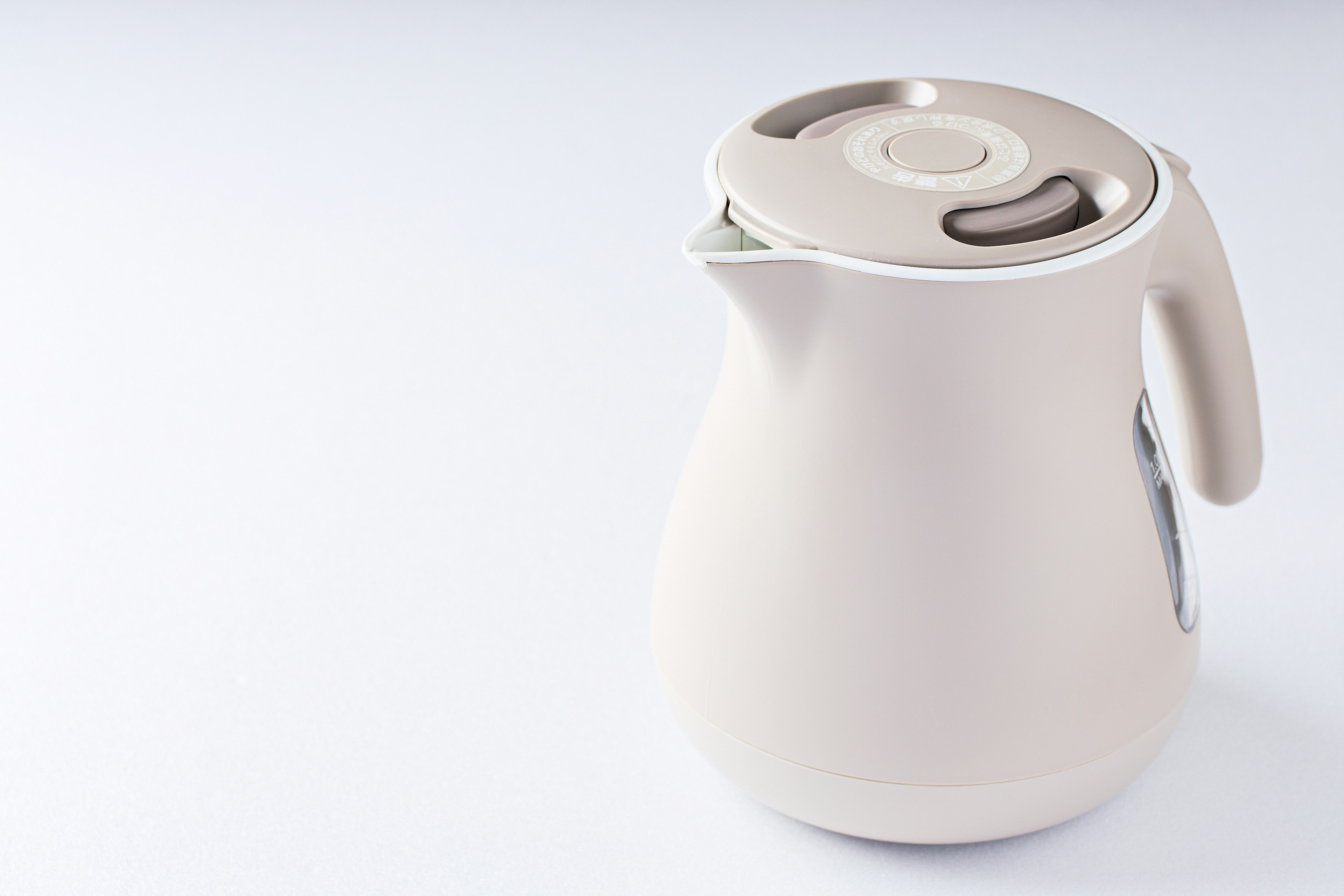 Side view of a beige electric kettle on a white background