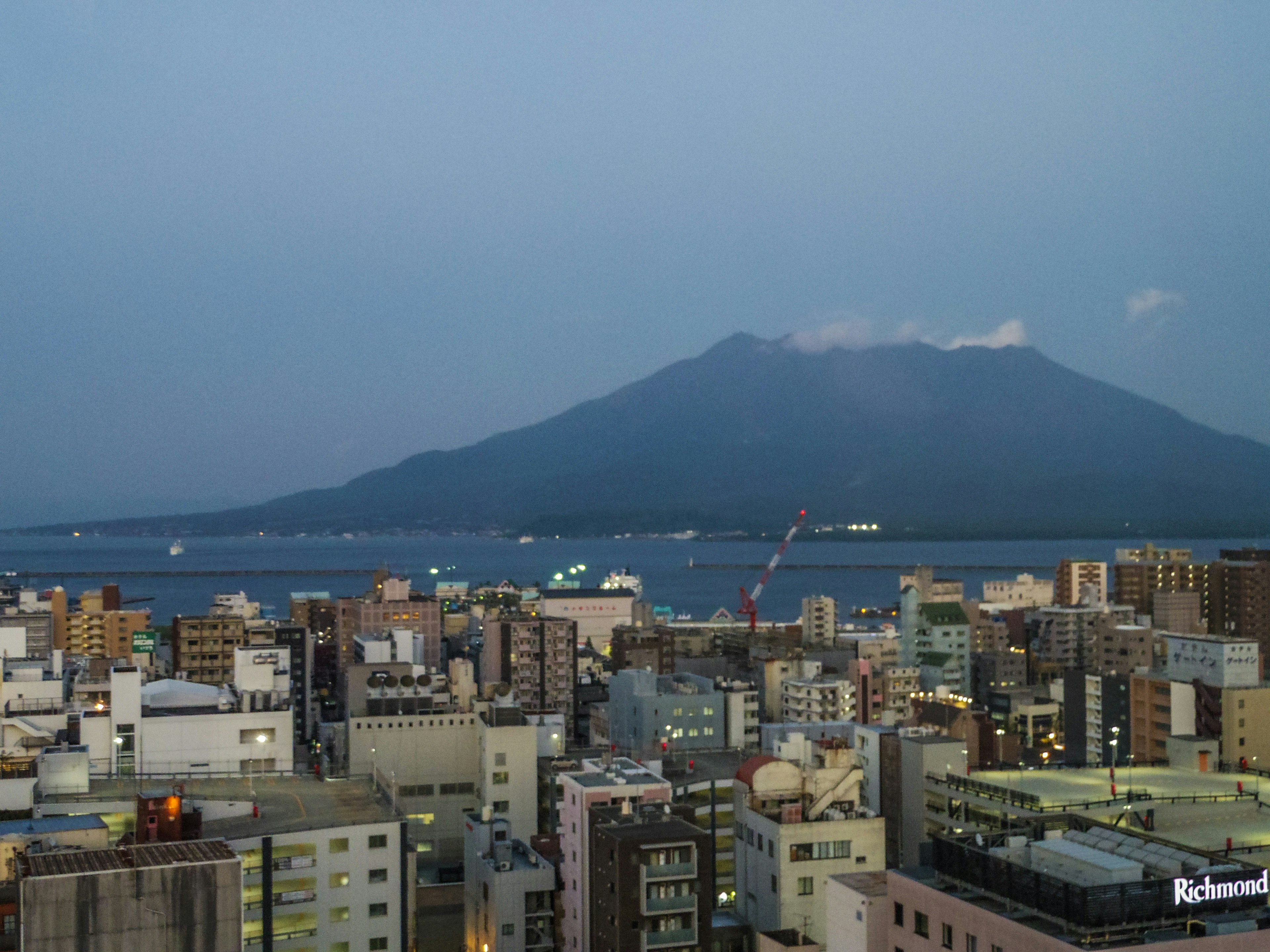 Stadtansicht in der Dämmerung mit dem Vulkan Sakurajima im Hintergrund