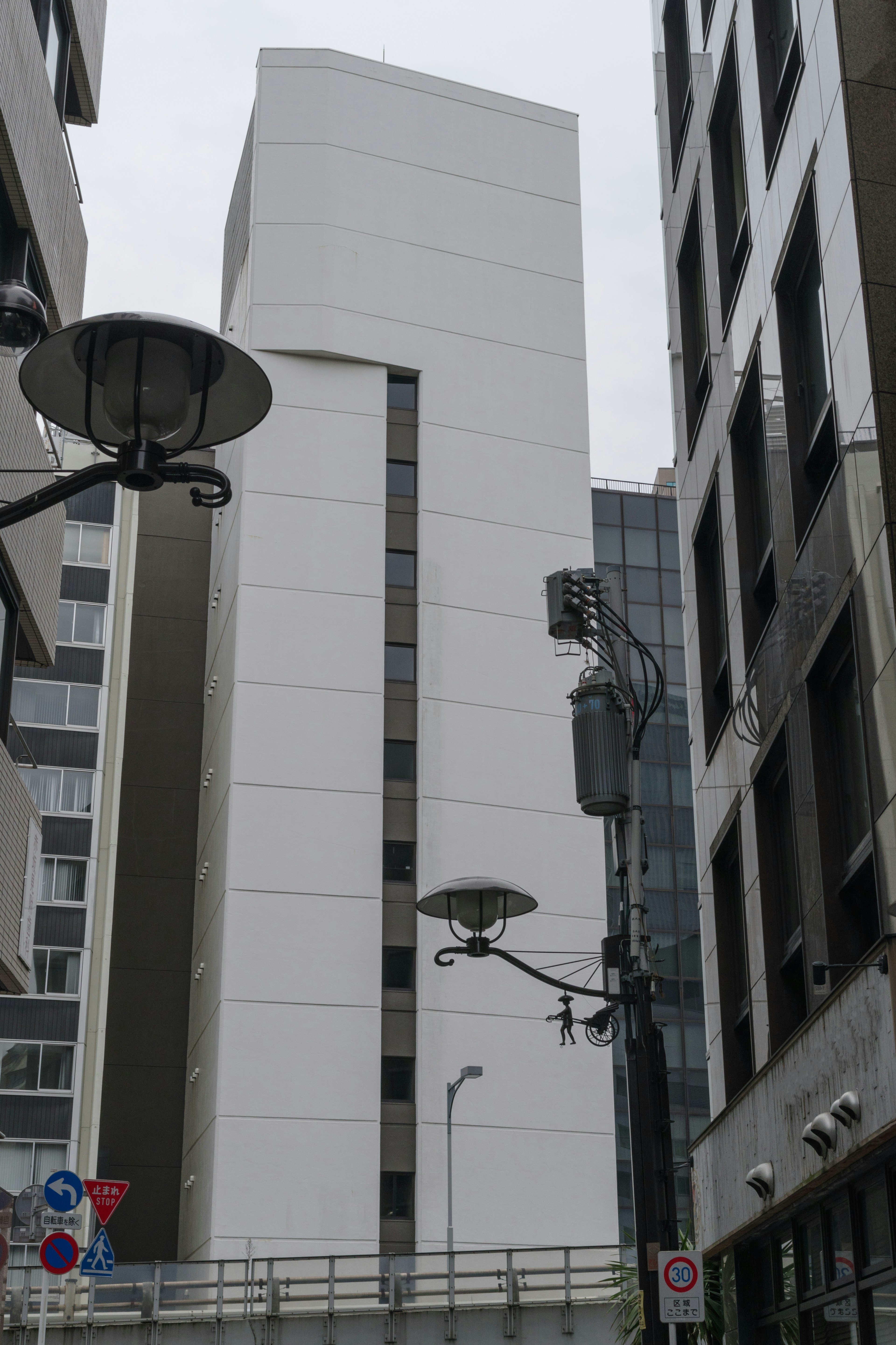 A modern building with a white facade stands in a narrow street