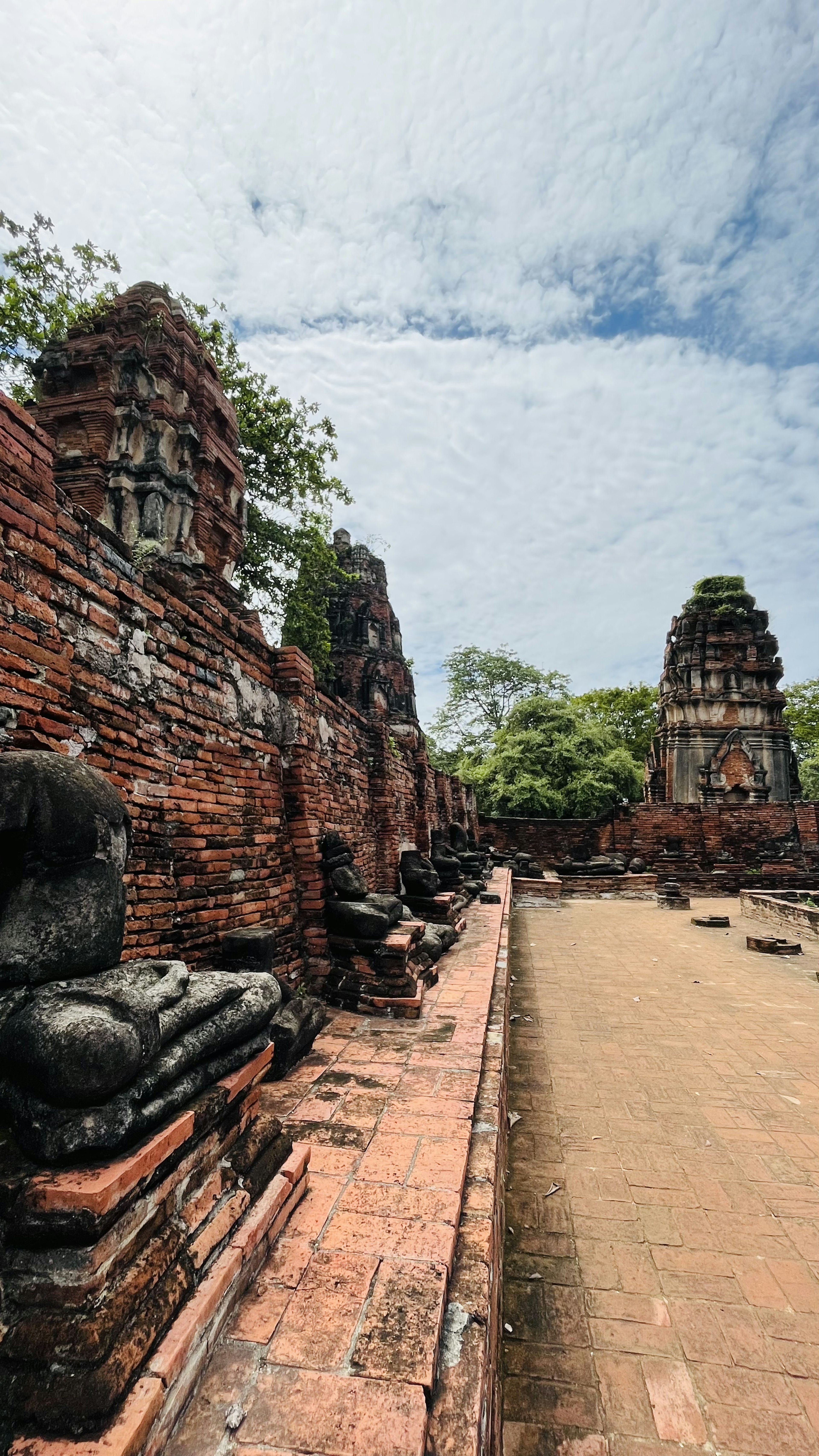 Ancient temple ruins with seated Buddha statues and lush greenery