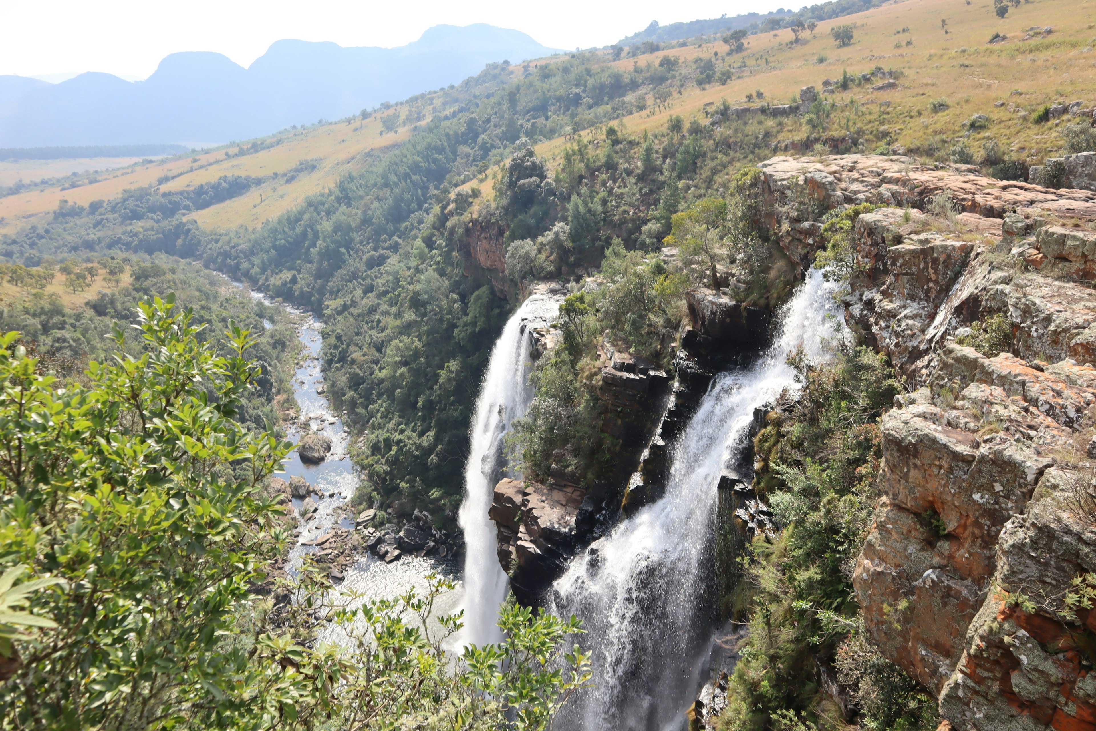 Pemandangan air terjun dikelilingi pegunungan subur