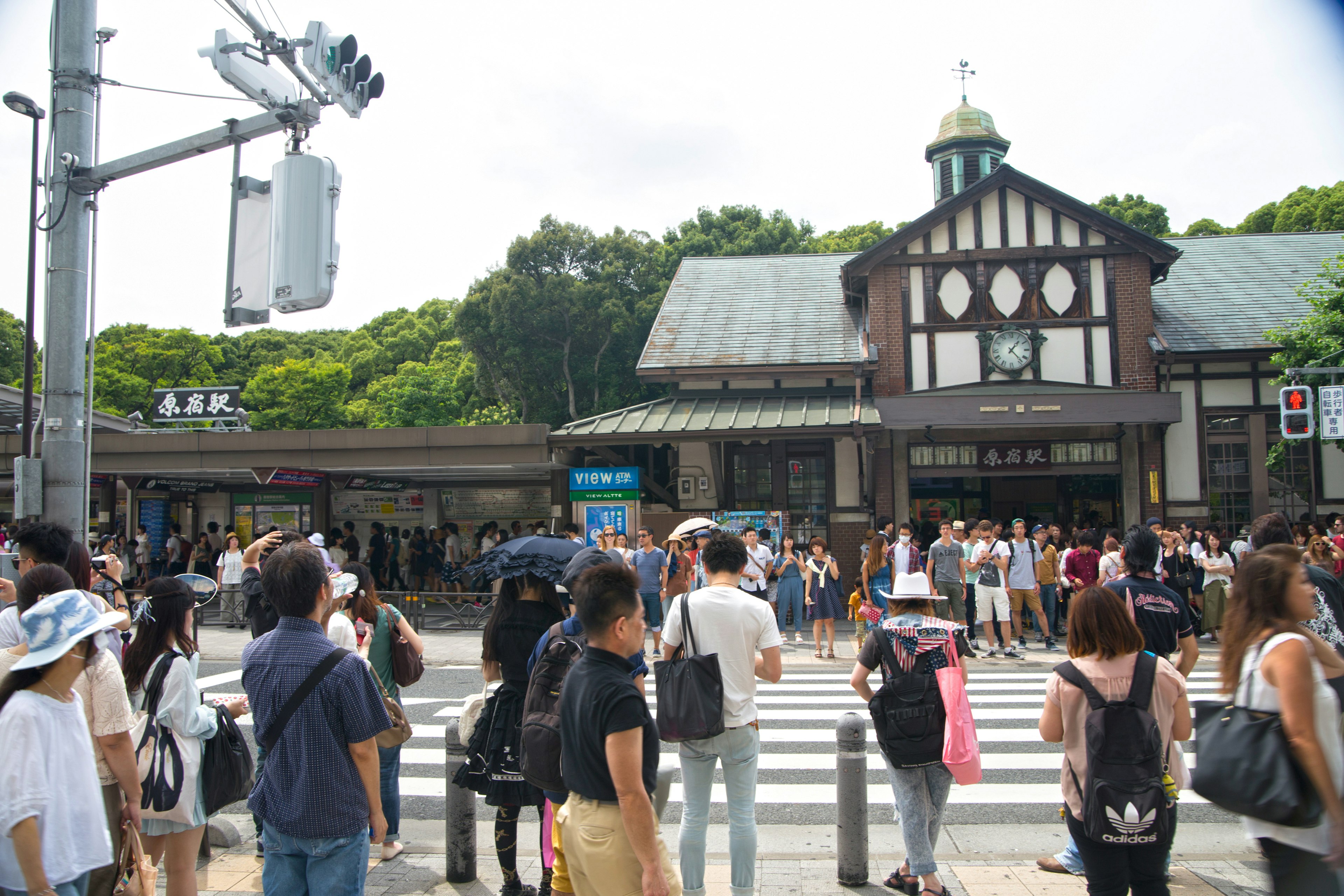 Crowded intersection with many people waiting Traditional station building visible in the background