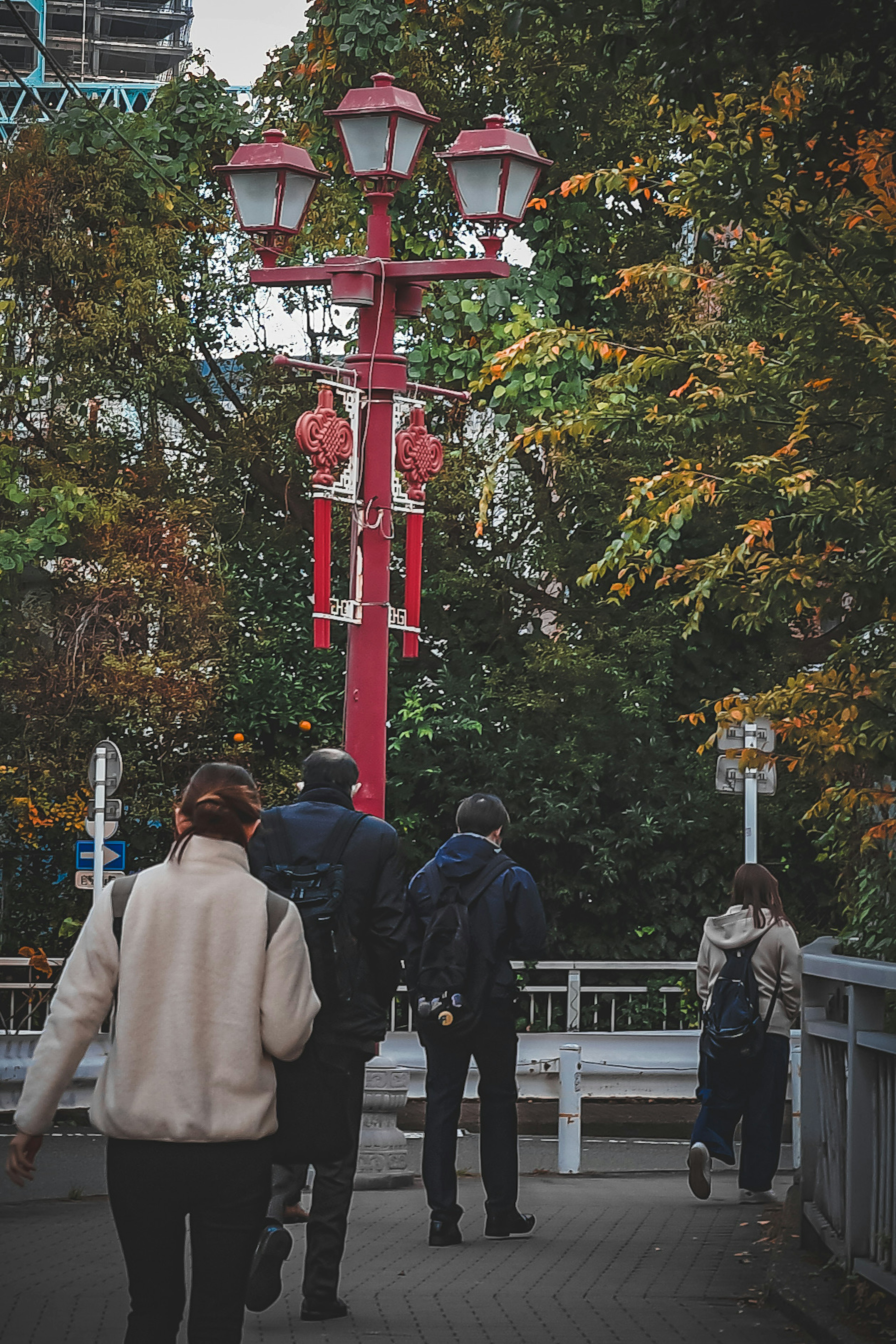 Menschen gehen auf einem Weg mit roten Straßenlaternen und Herbstbäumen