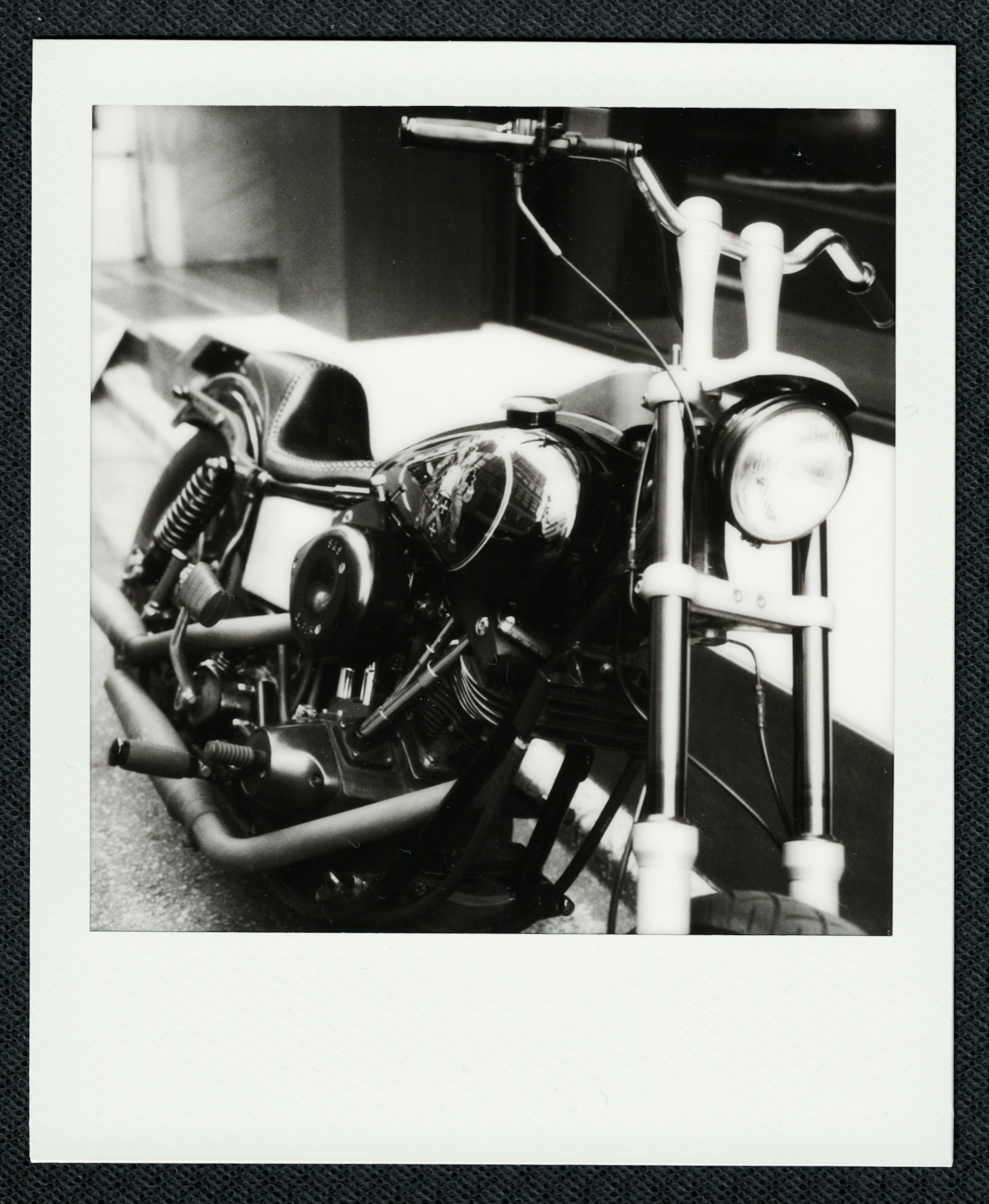 Close-up of a black and white Polaroid photo of a motorcycle featuring a modern design