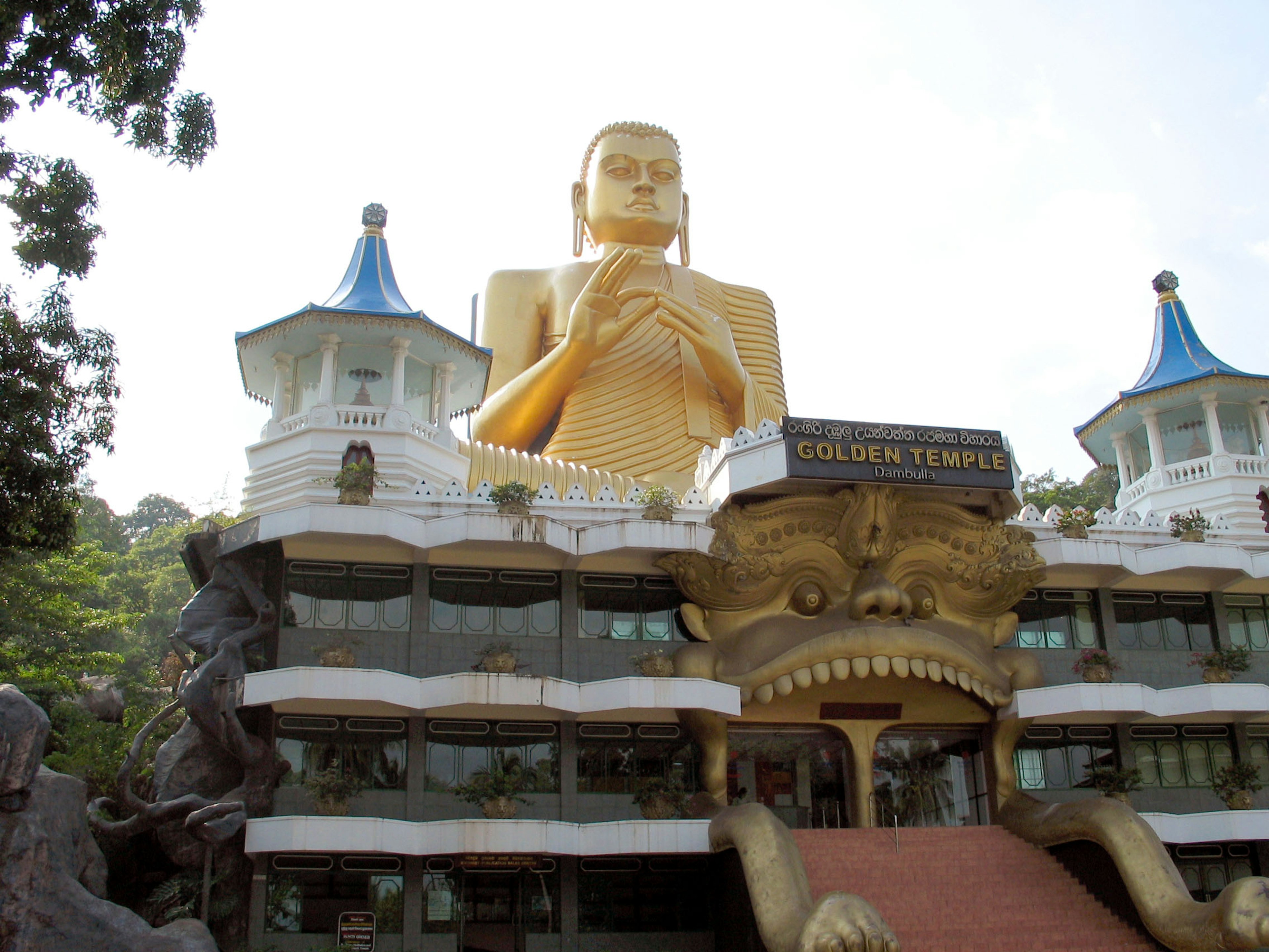 Exterior view of a temple featuring a large golden Buddha statue