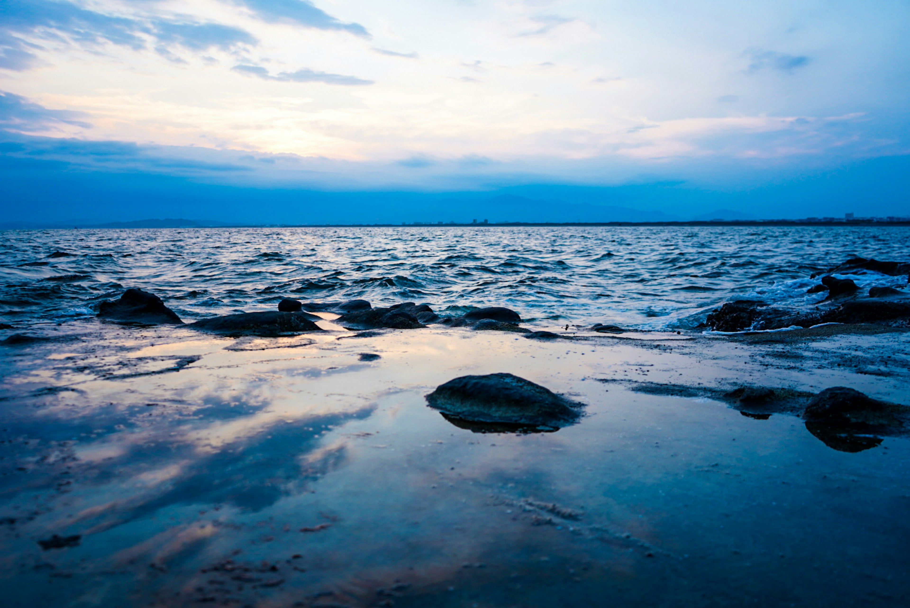 Rocky shoreline at dusk with reflections on the water