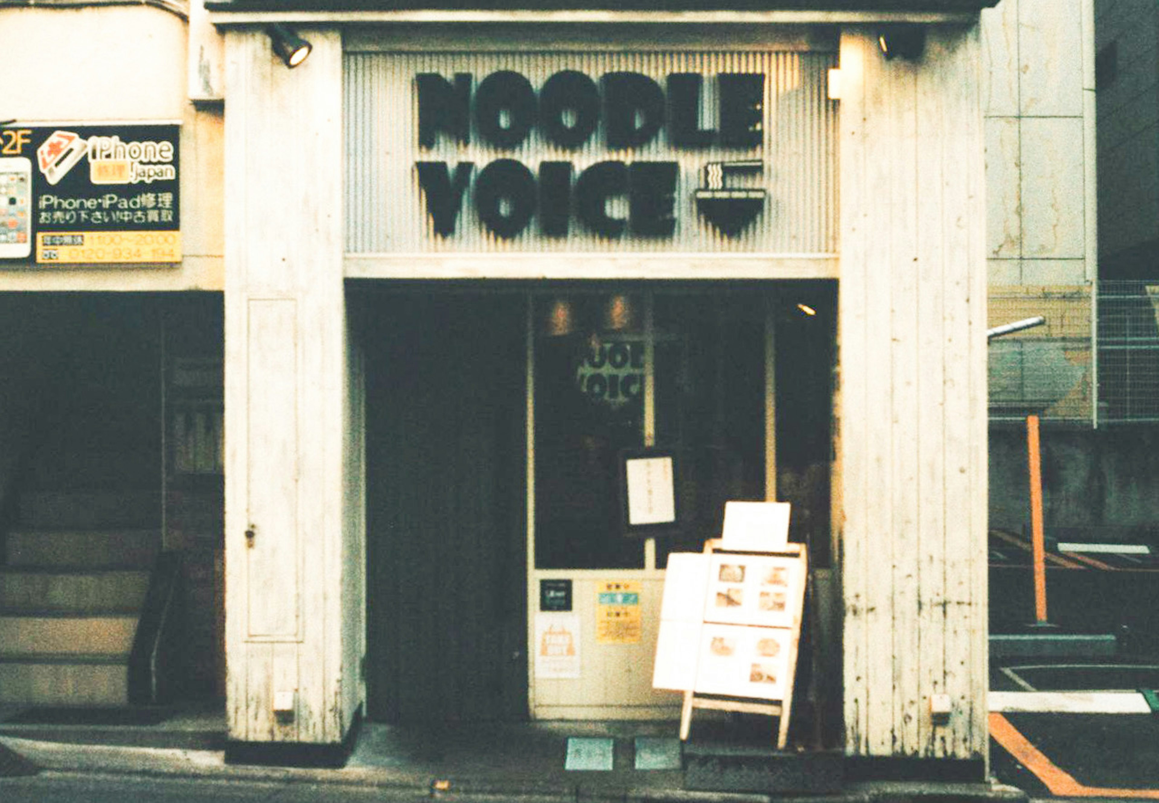 Exterior del restaurante Noodle Voice con letrero brillante y pared blanca