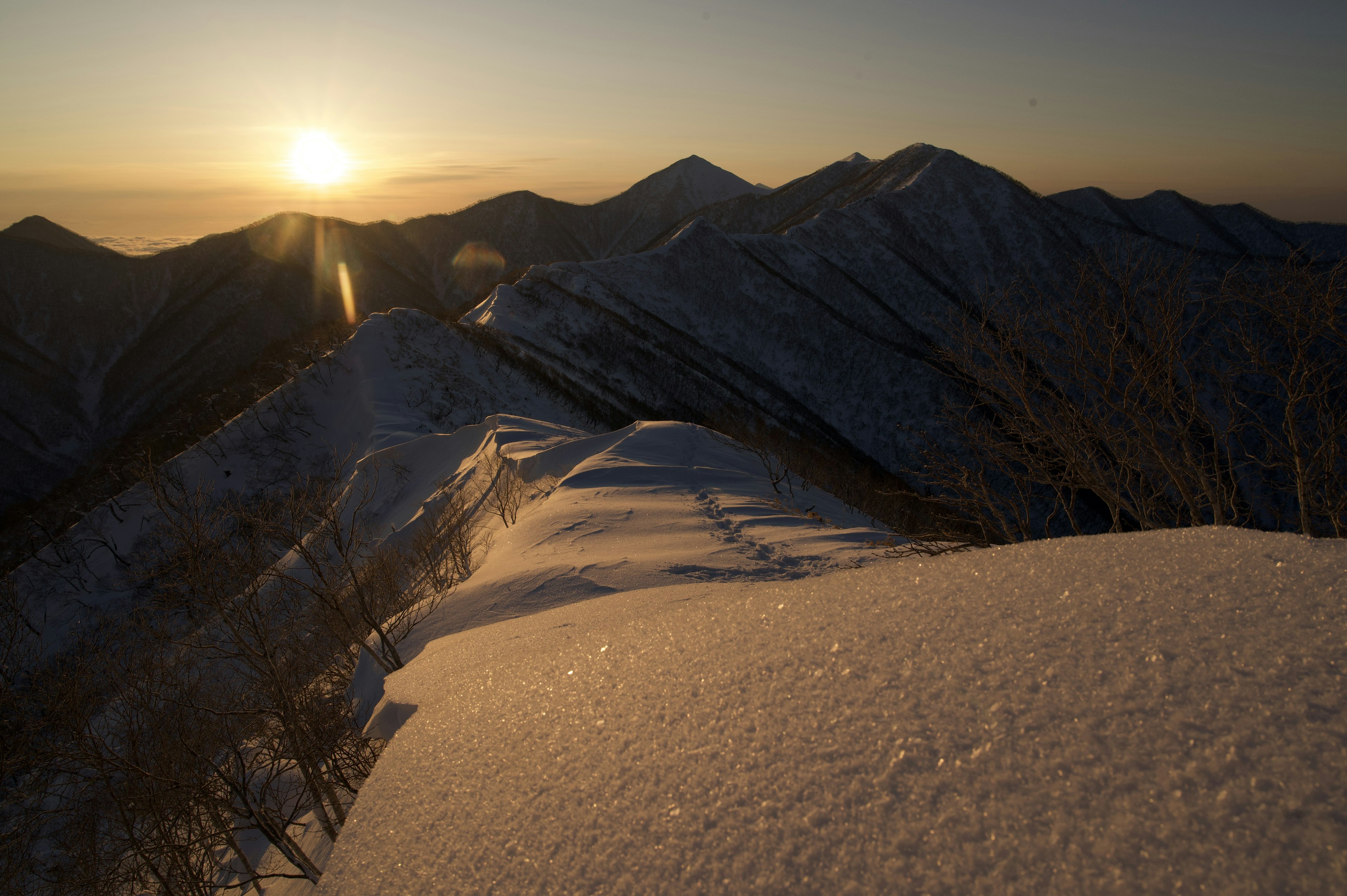 Montagne innevate con un sole che sorge