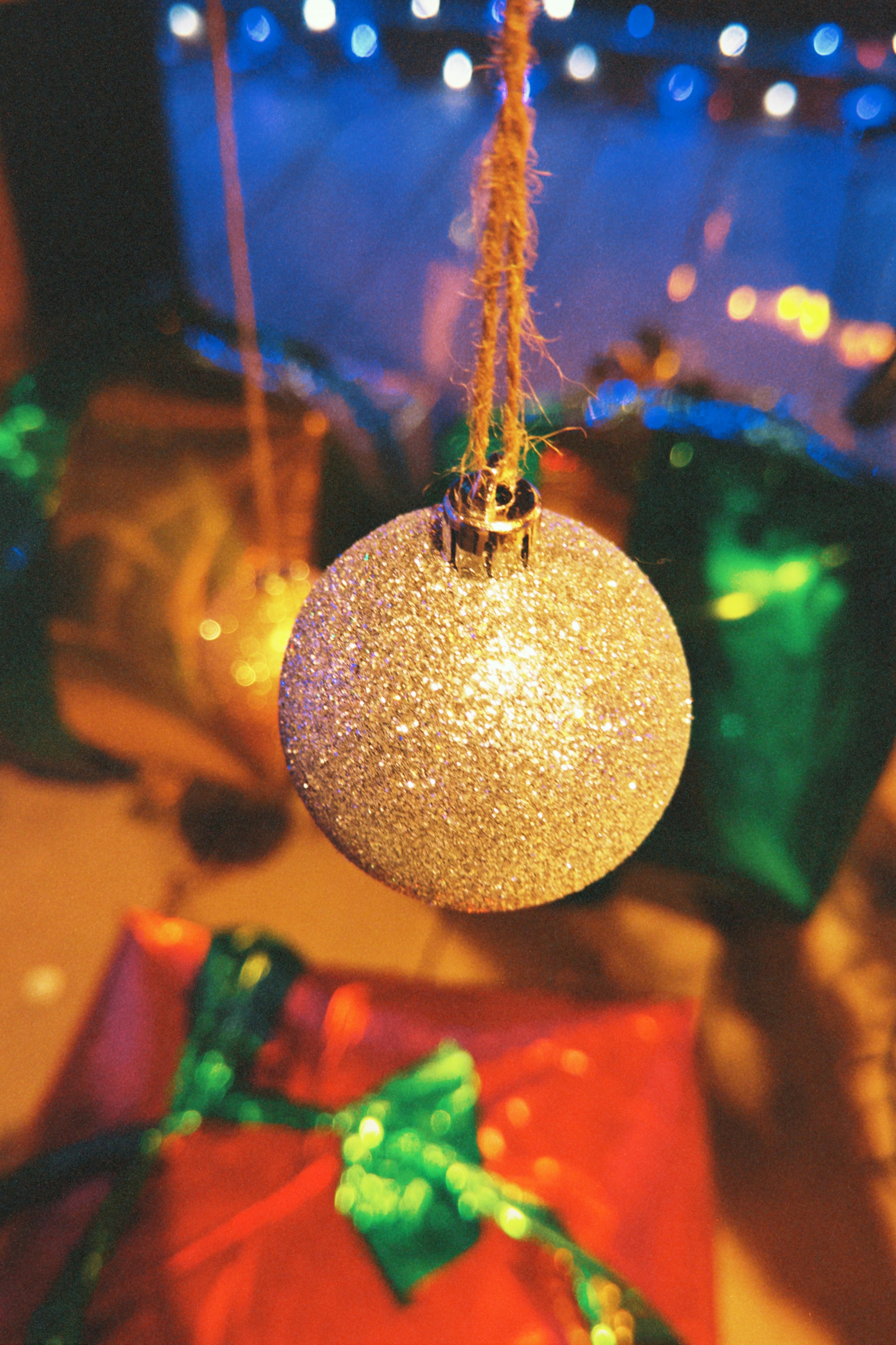 Weihnachtsornament hängt mit bunten Geschenken im Hintergrund