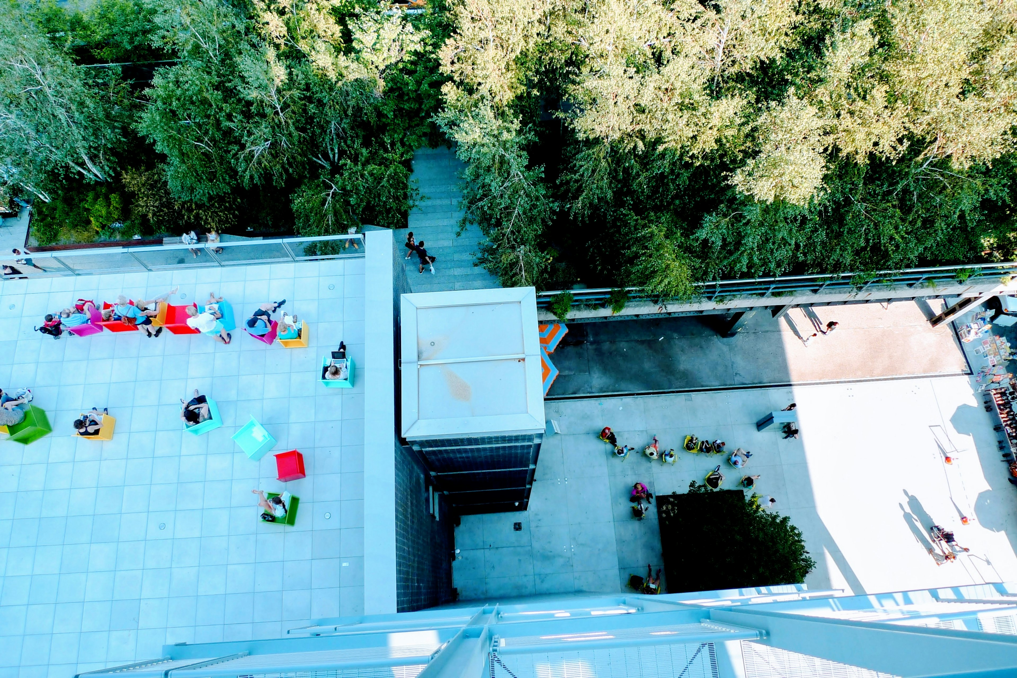 Aerial view of a rooftop patio with people gathered surrounded by greenery