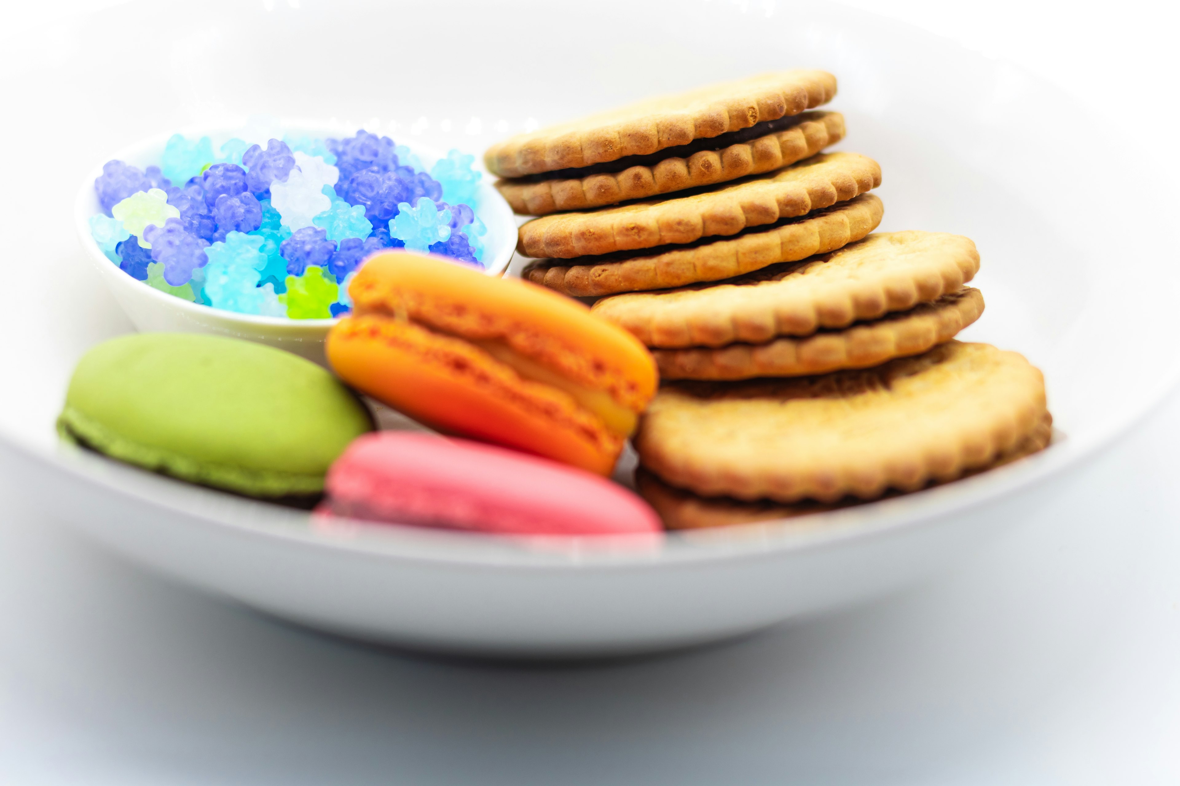 A white plate with colorful macarons and biscuits arranged attractively