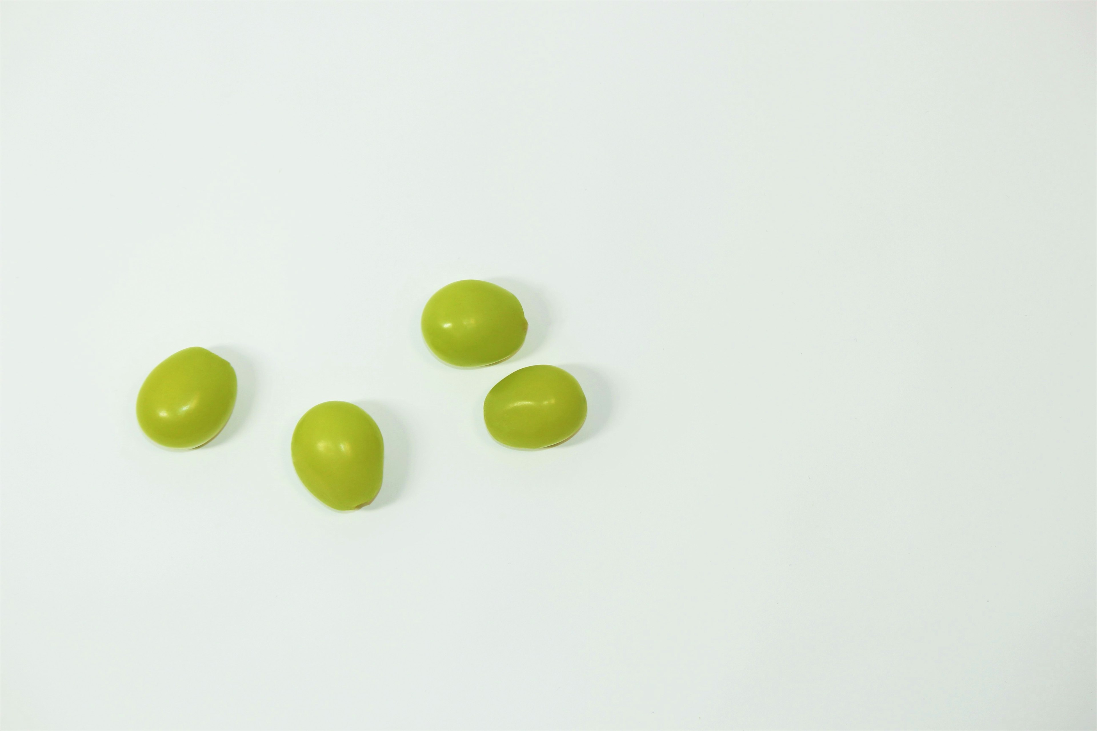 Four green candies arranged on a white background