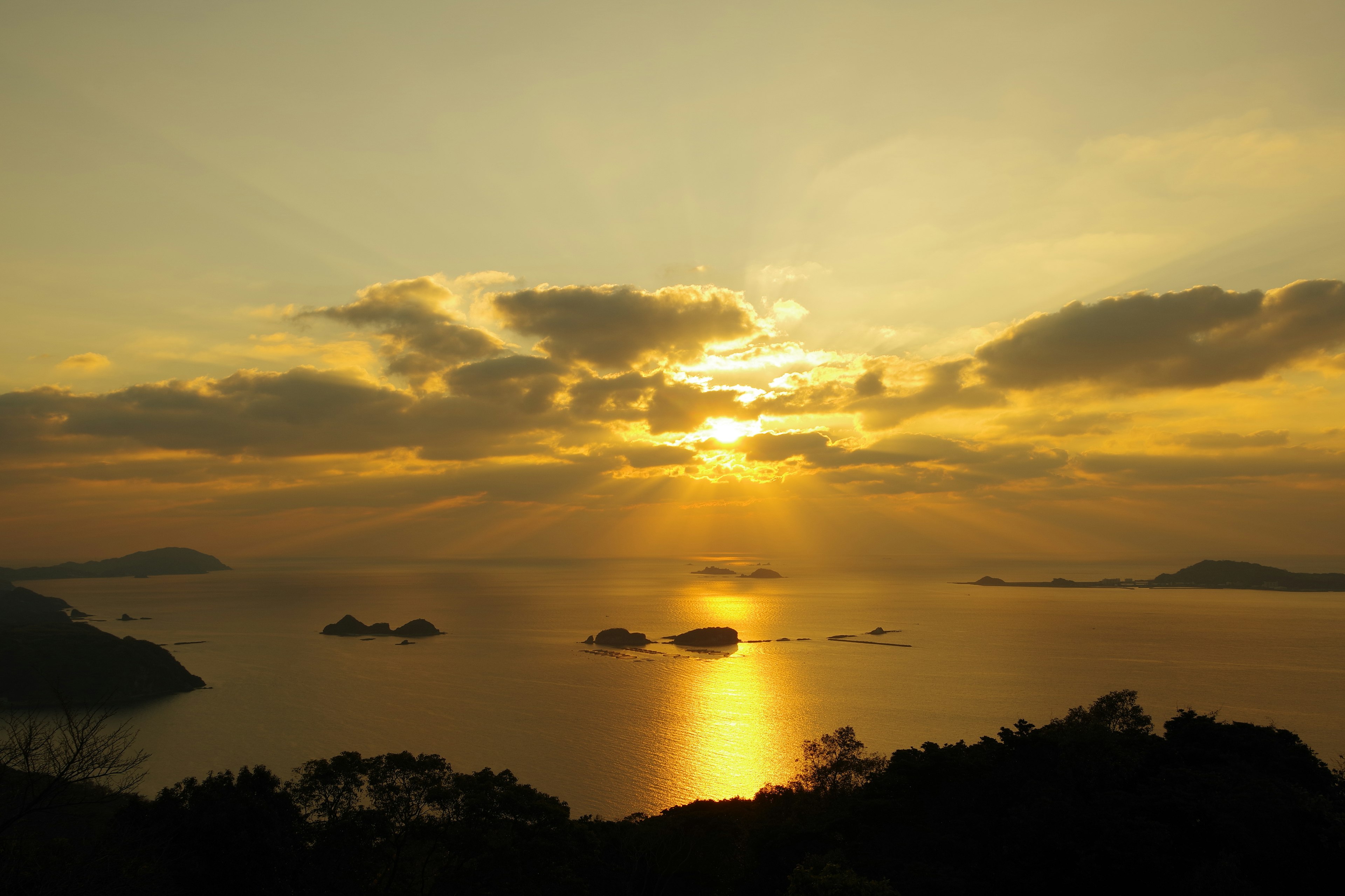 Malerischer Sonnenuntergang über dem Meer mit mehreren Inseln und schönen Wolken