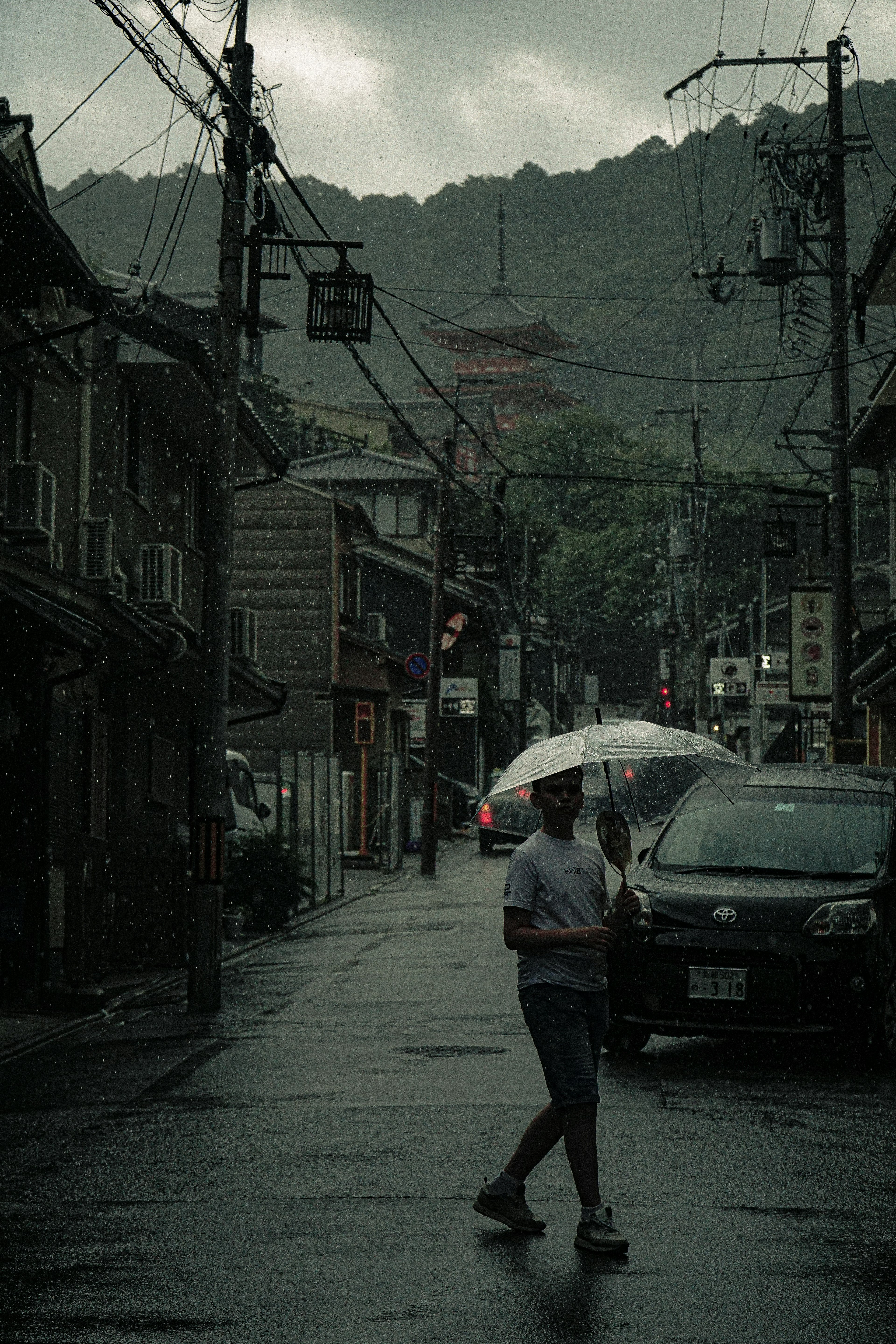 雨の中を歩く人と古い建物のある街並み