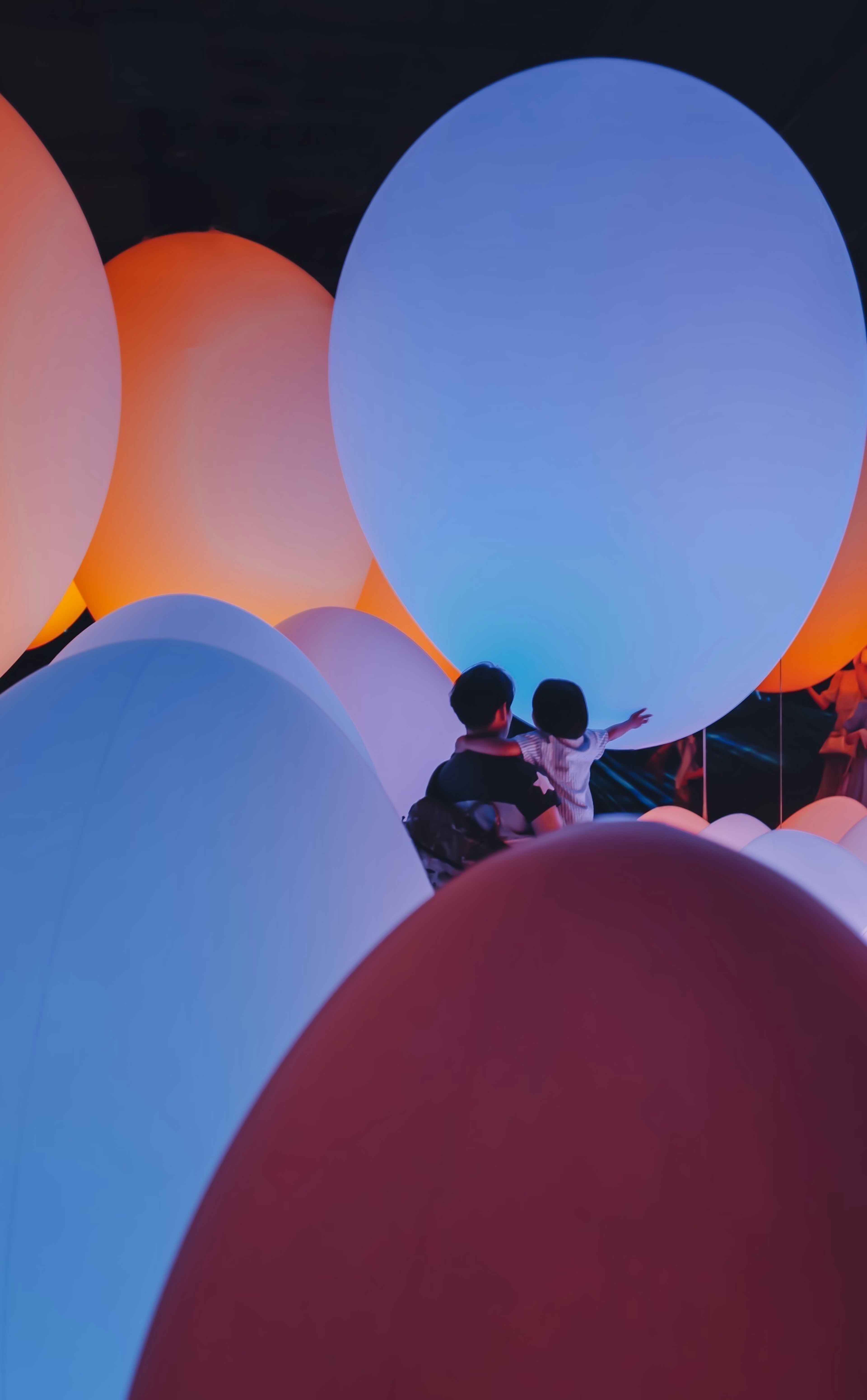 Silhouette d'un parent et d'un enfant entourés d'objets en forme d'œuf colorés