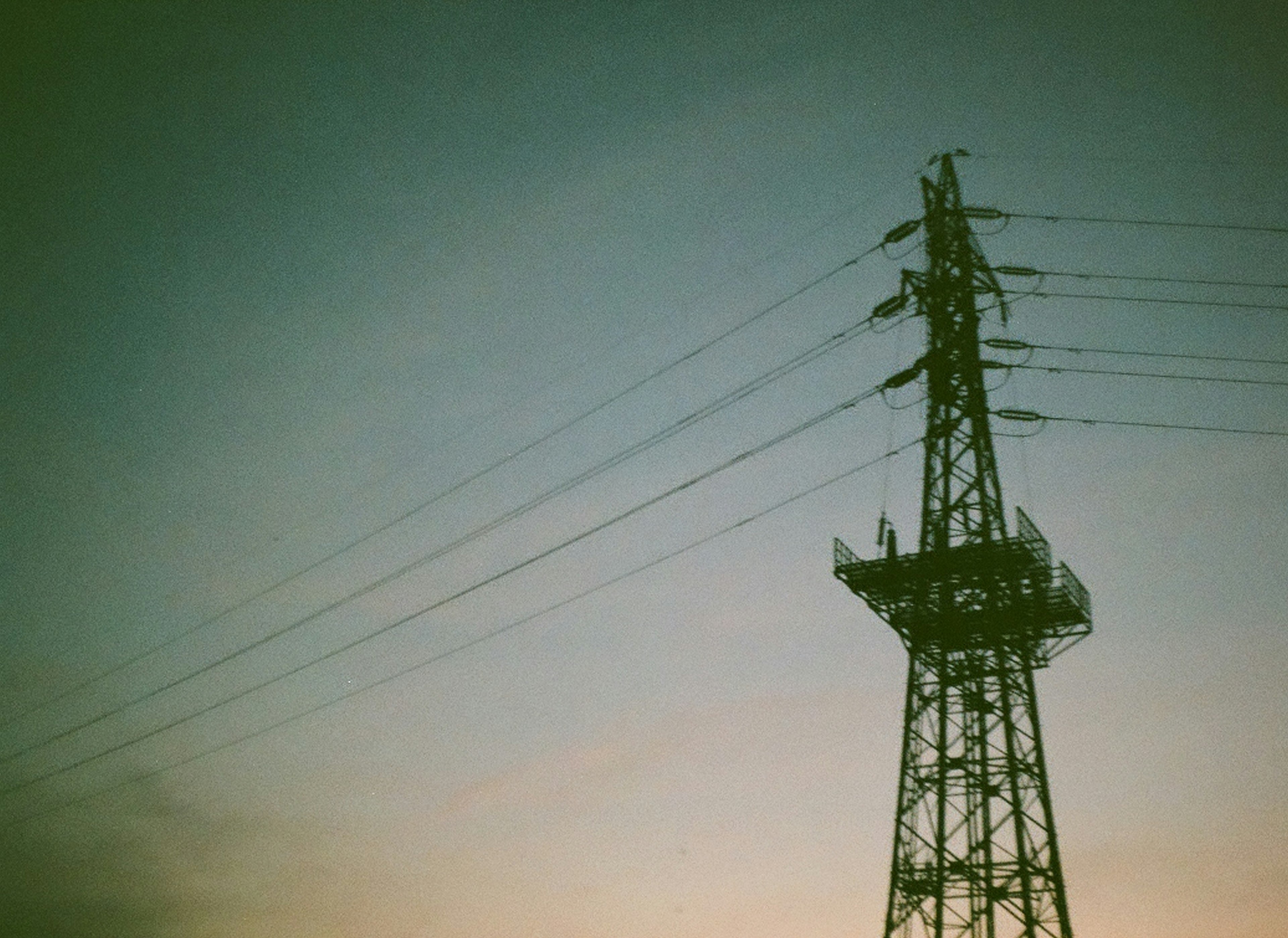 夕暮れの空に立つ鉄塔と電線のシルエット