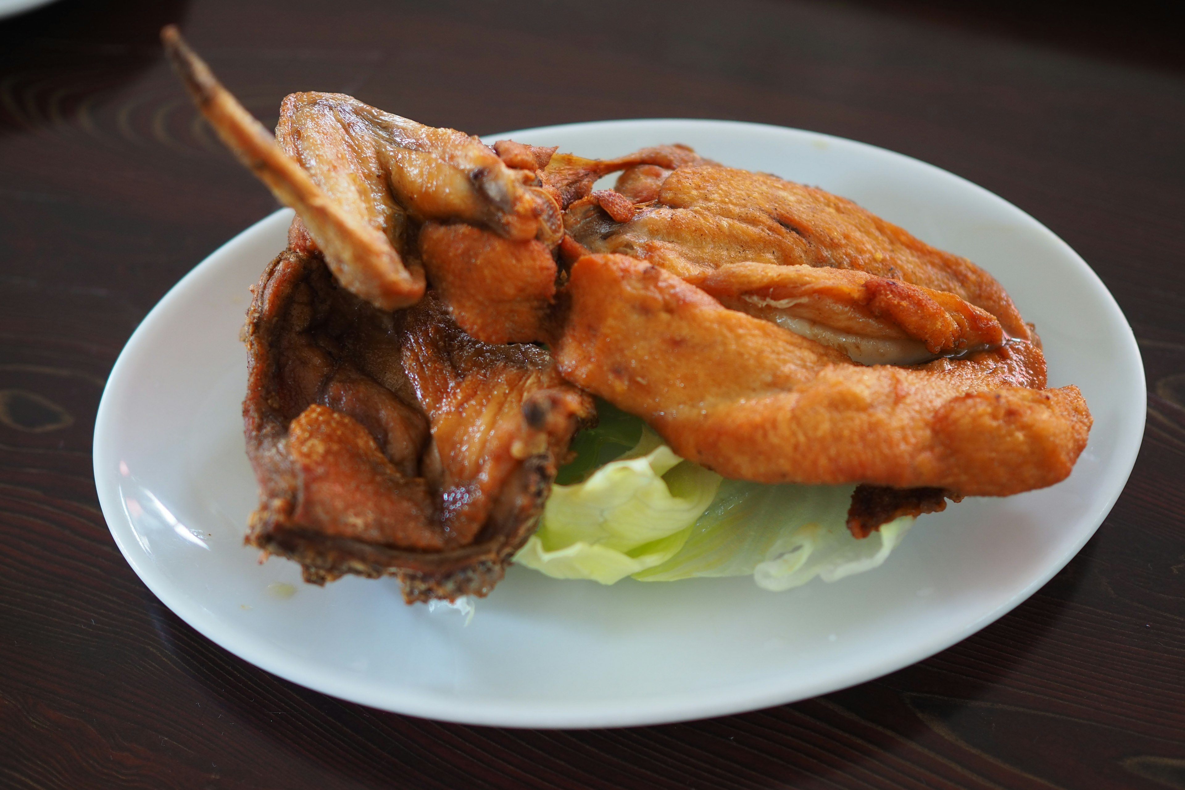 Piring sayap ayam goreng yang disajikan di atas selada