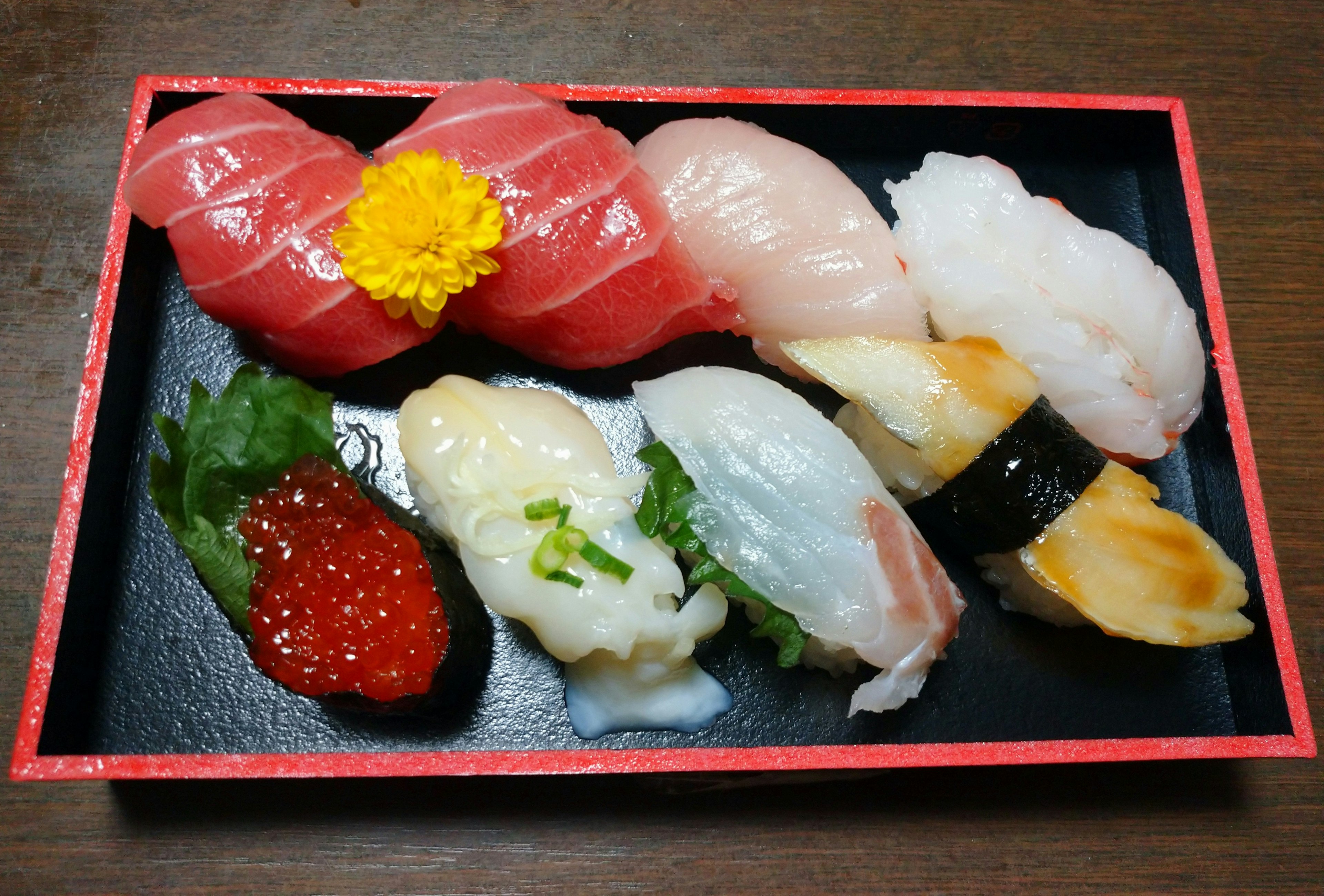 Assortiment de sushi coloré sur un plateau noir avec différents types de poisson et garnitures