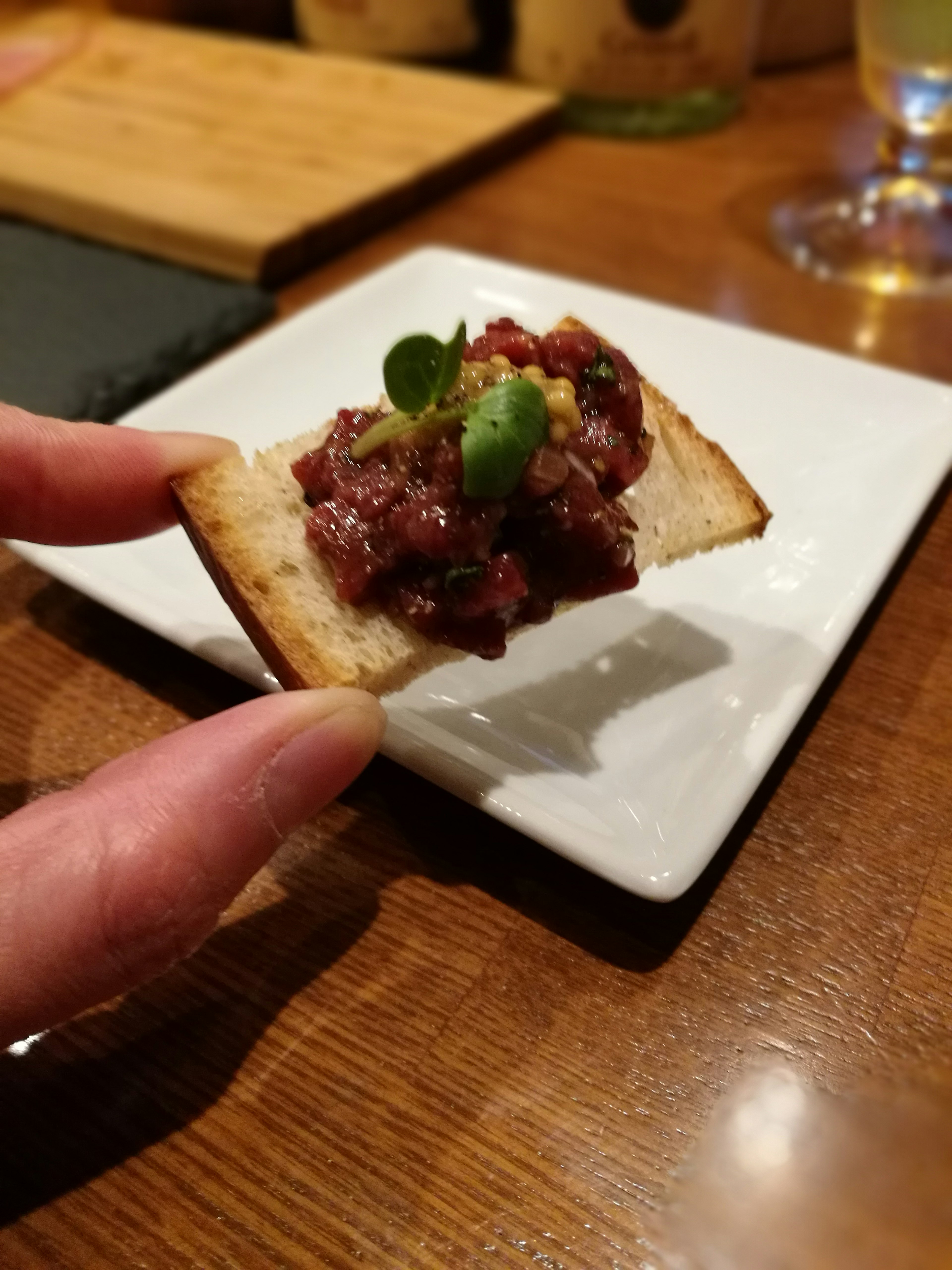 手に持たれたパンの上に肉のタルタルが載っている