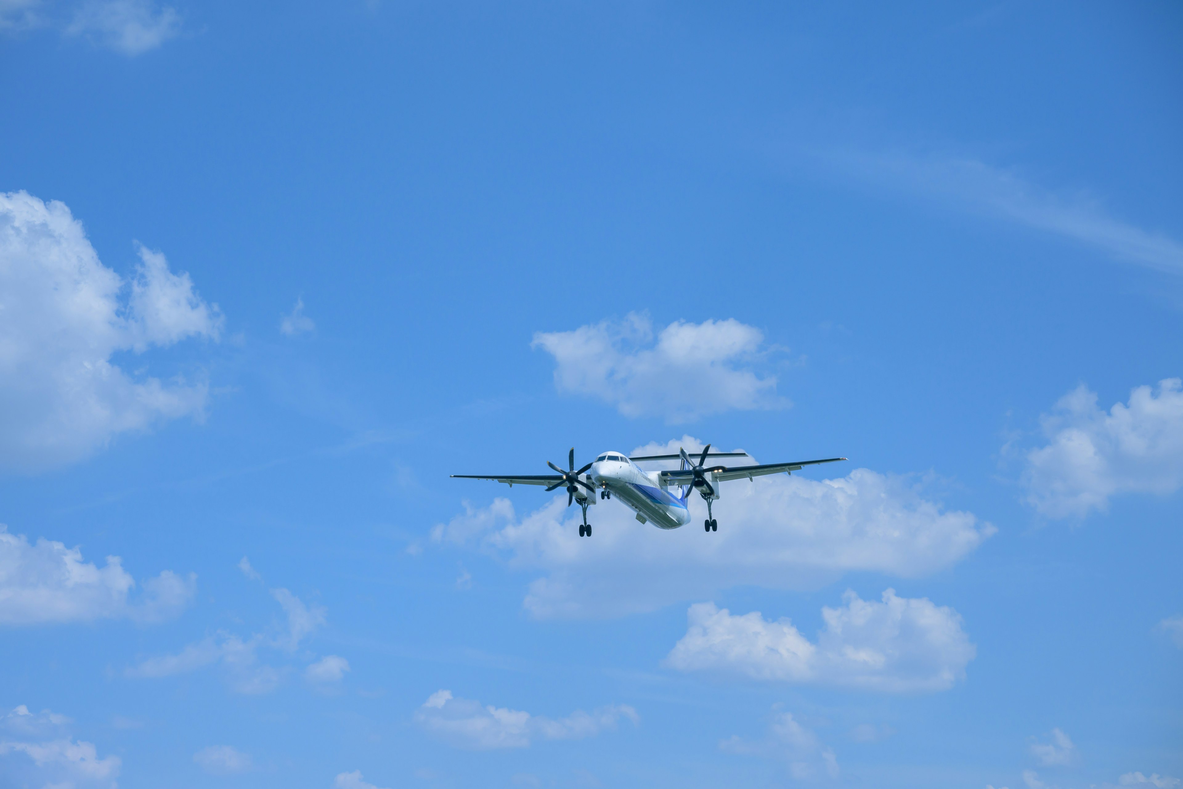 Avión volando en un cielo azul con nubes blancas