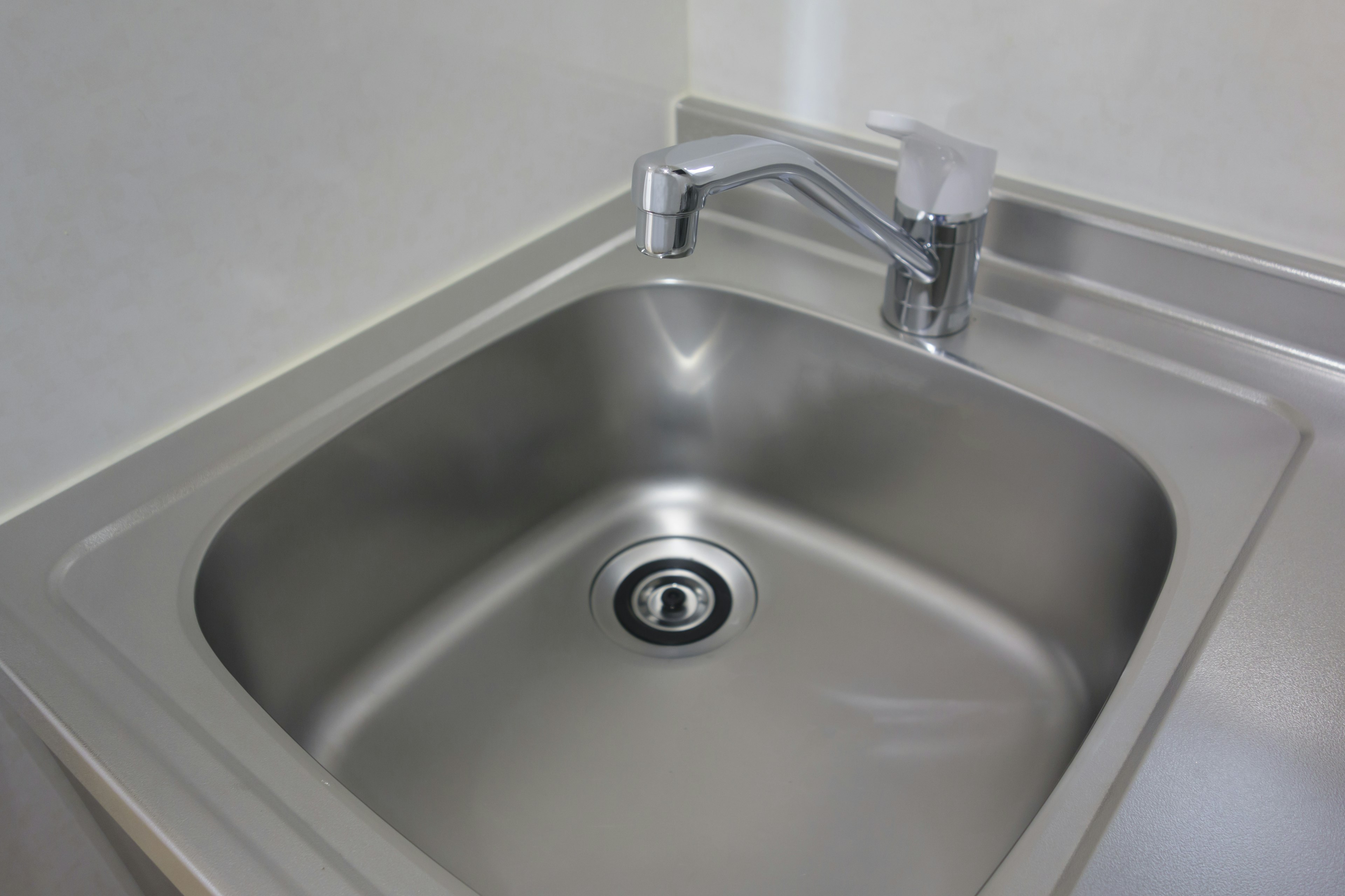 A stainless steel sink with a faucet in a kitchen setting