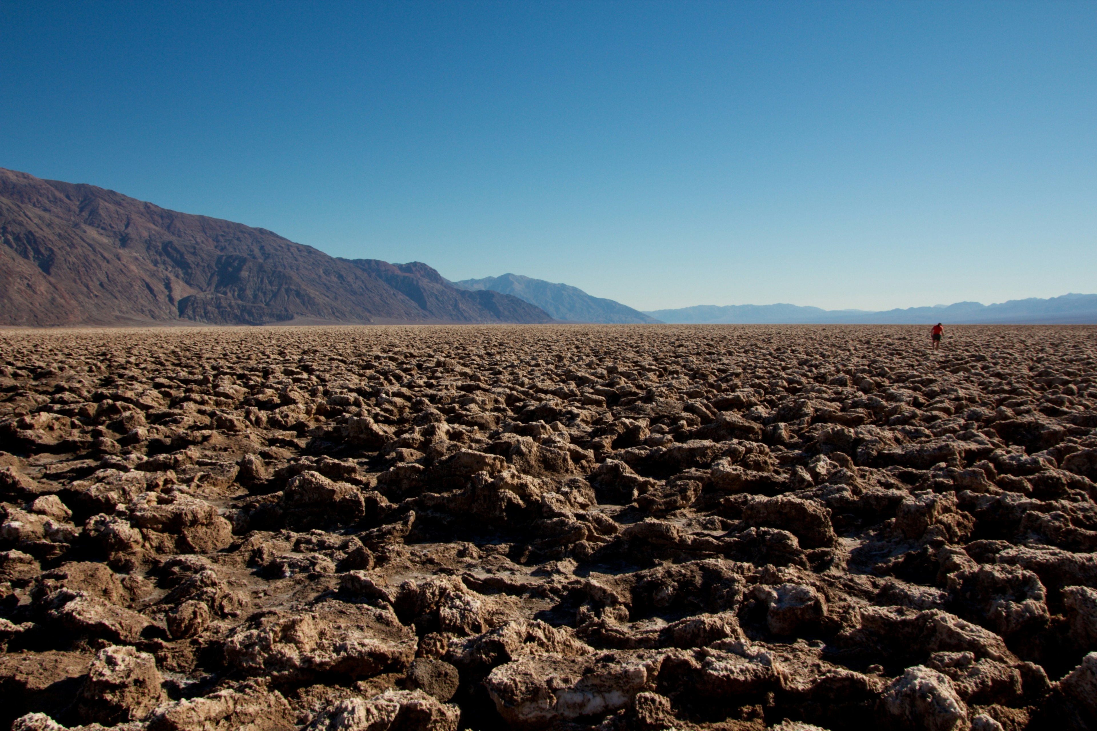 Paesaggio secco della Death Valley con terreno roccioso e montagne in lontananza