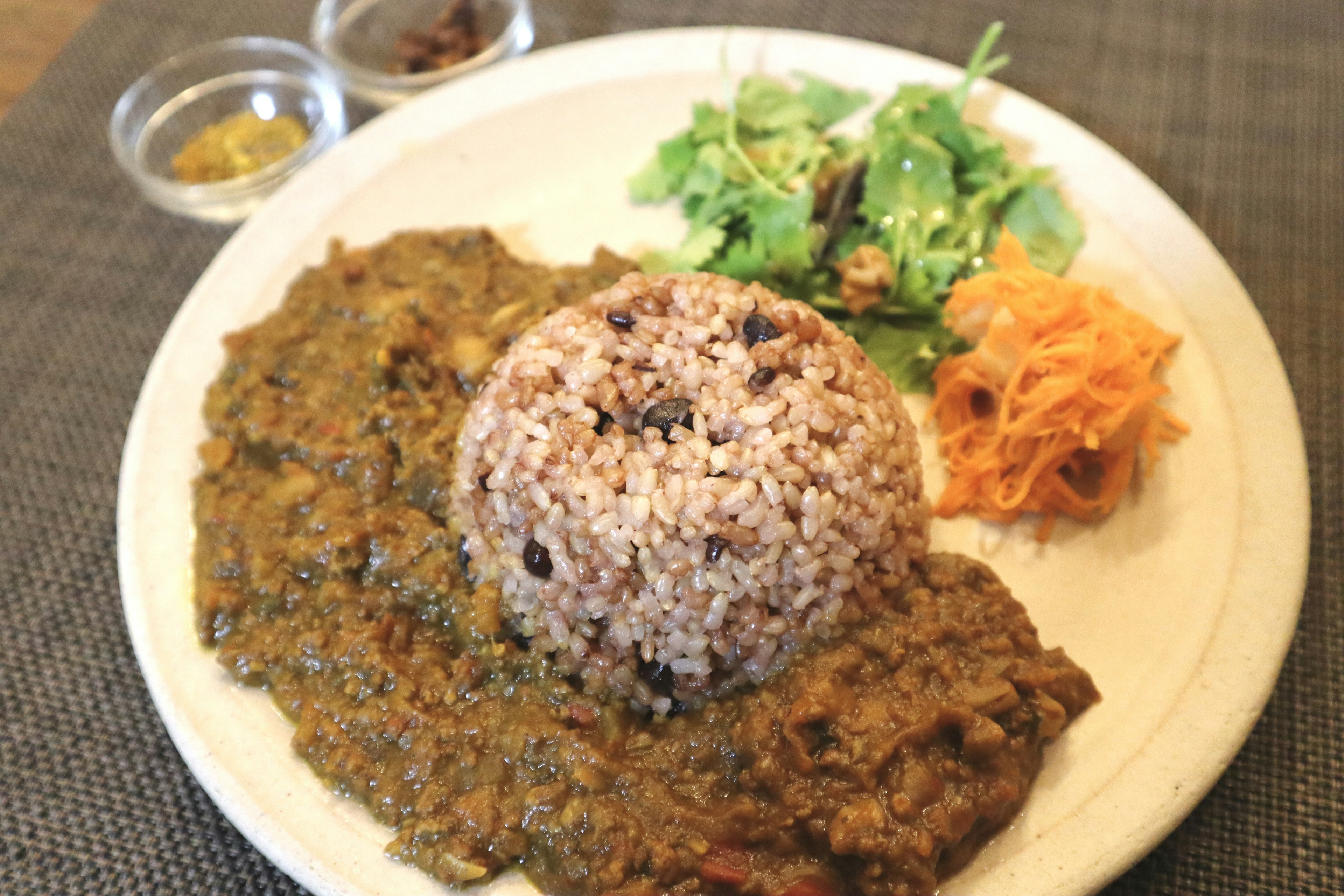 Ein Teller mit braunem Reis, Currysoße und verschiedenen Gemüsesorten