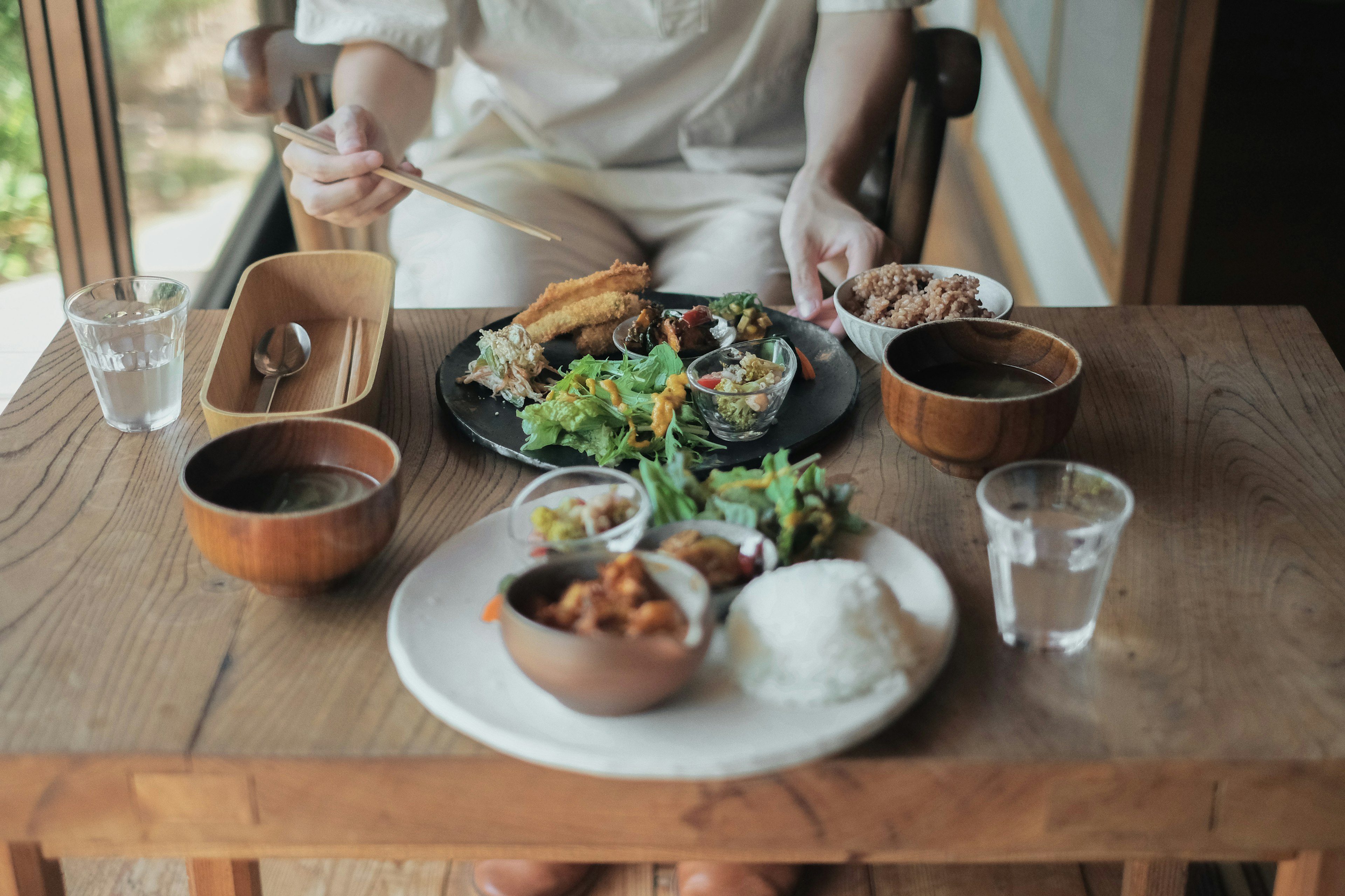 A person enjoying a variety of delicious dishes and drinks on a wooden table