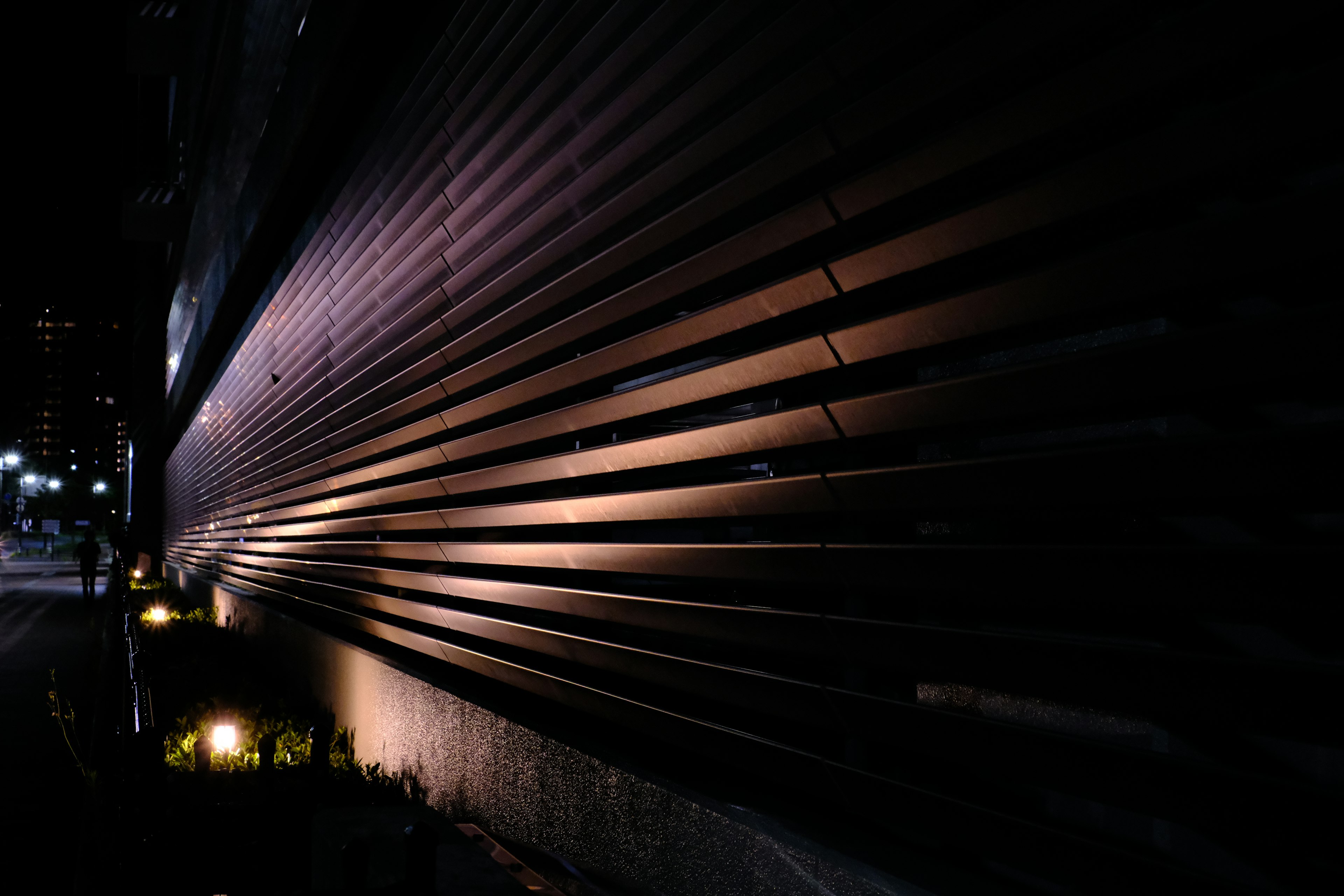 Mur en lattes de bois brillant d'un bâtiment la nuit dans un cadre urbain