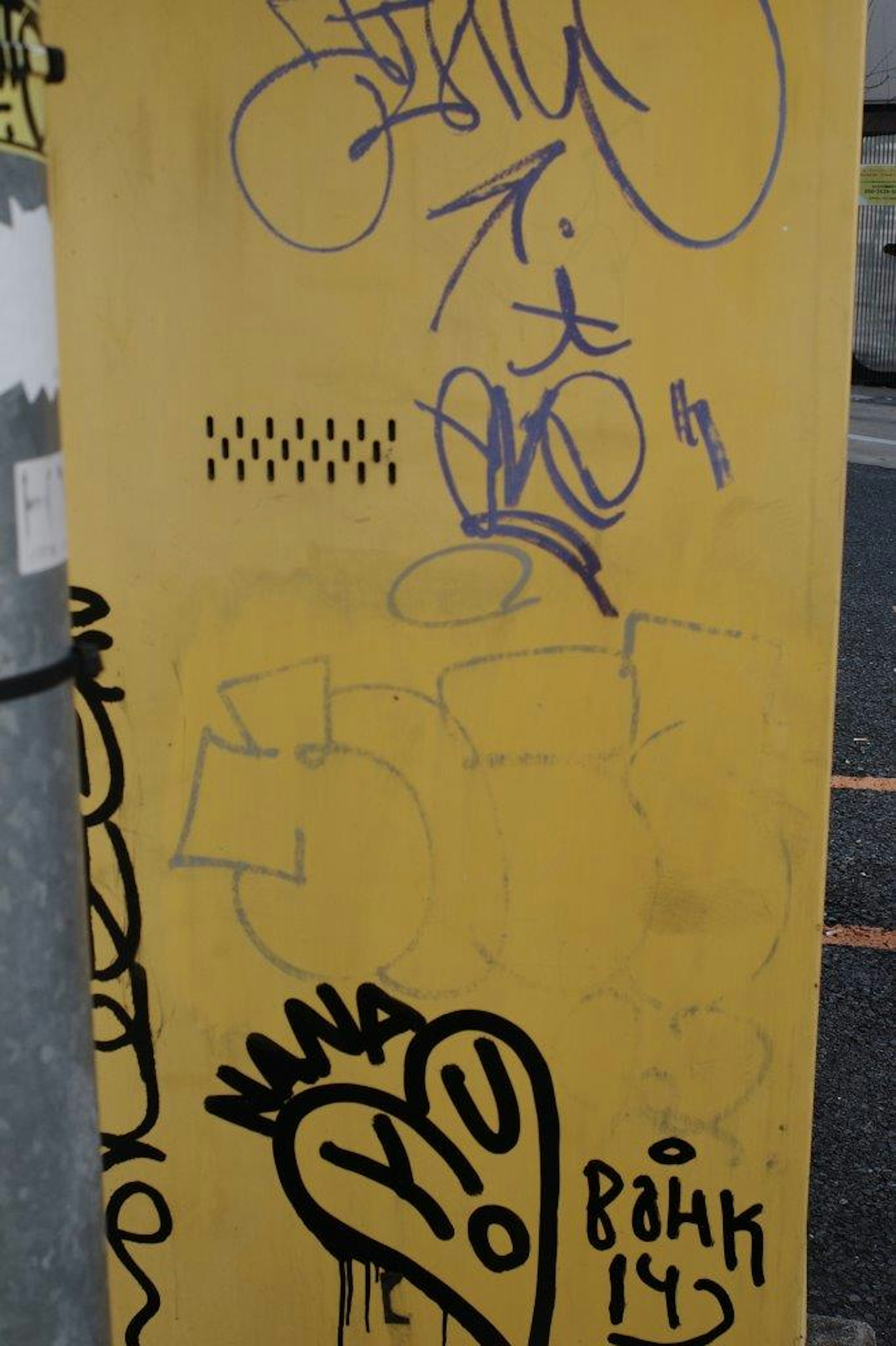 Verschiedene Graffiti-Designs auf einer gelben Wand mit bunten Tags und Illustrationen