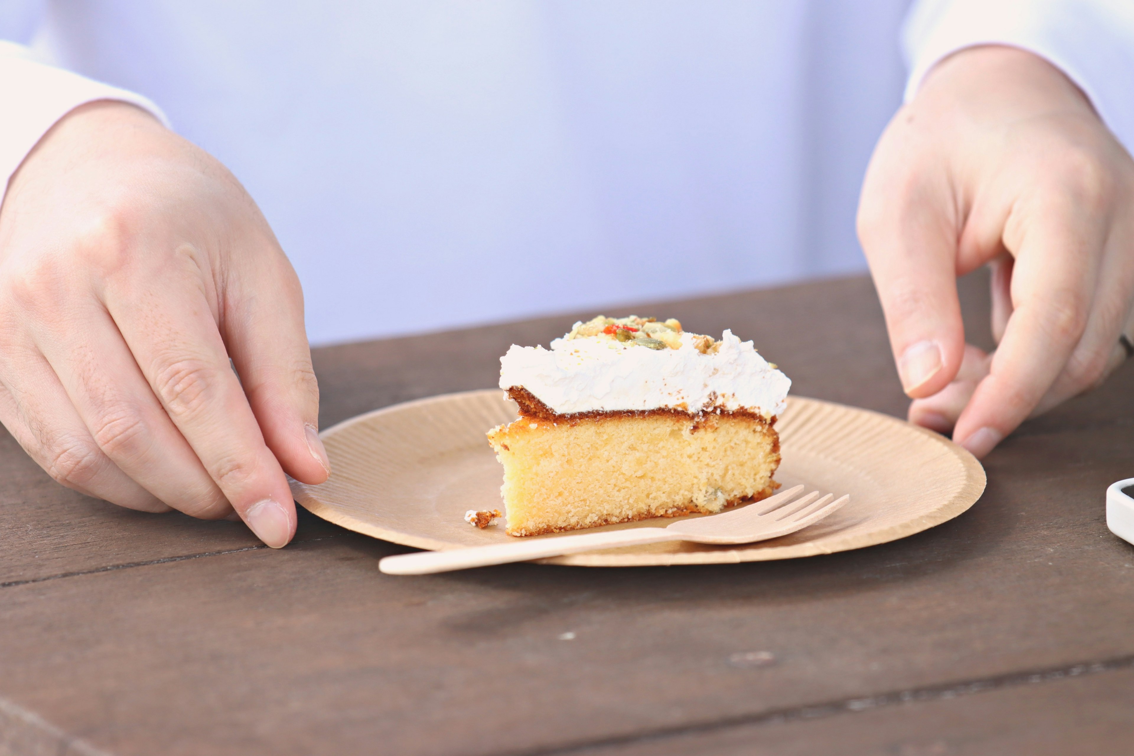 Mains plaçant une tranche de gâteau sur une assiette en bois