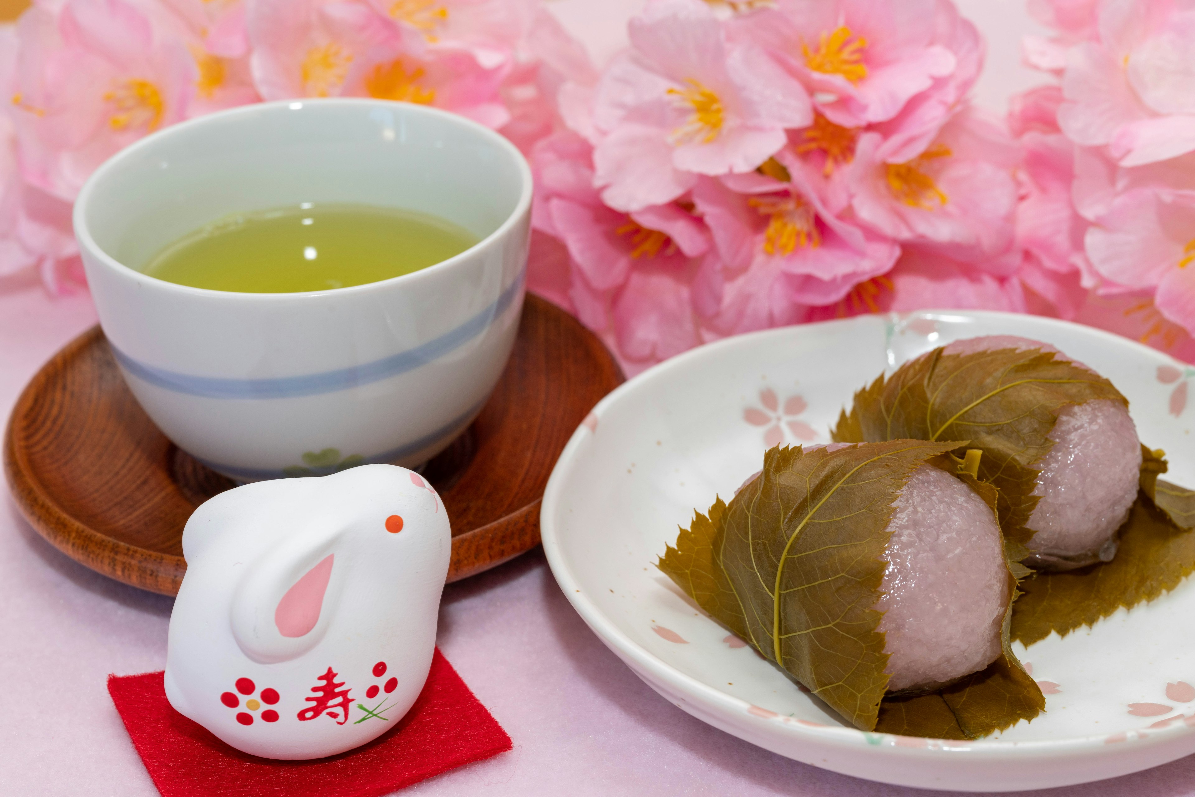 Thé japonais et sakura mochi sur une table avec des cerisiers en fleurs