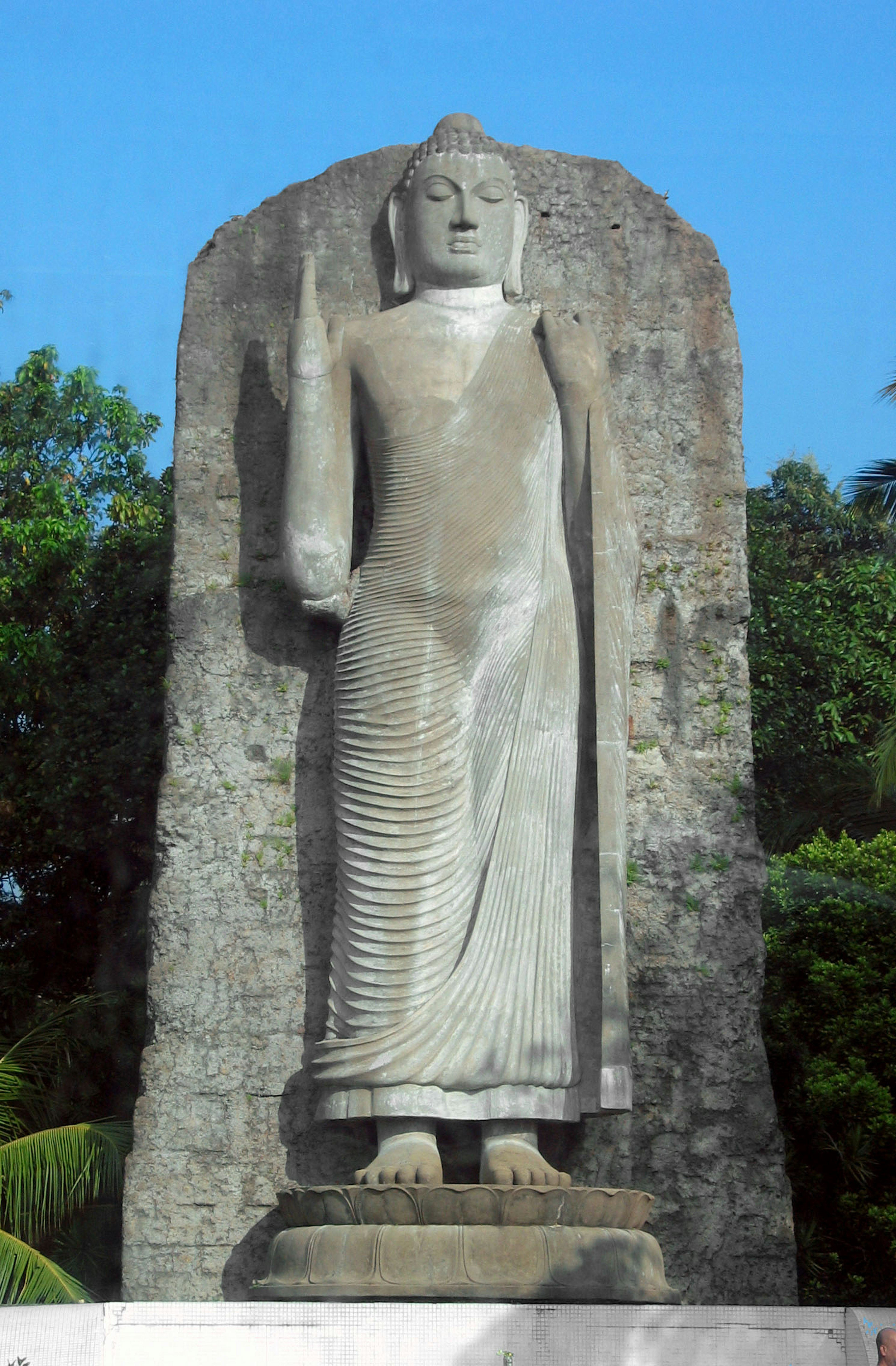 Standing stone Buddha statue against a blue sky