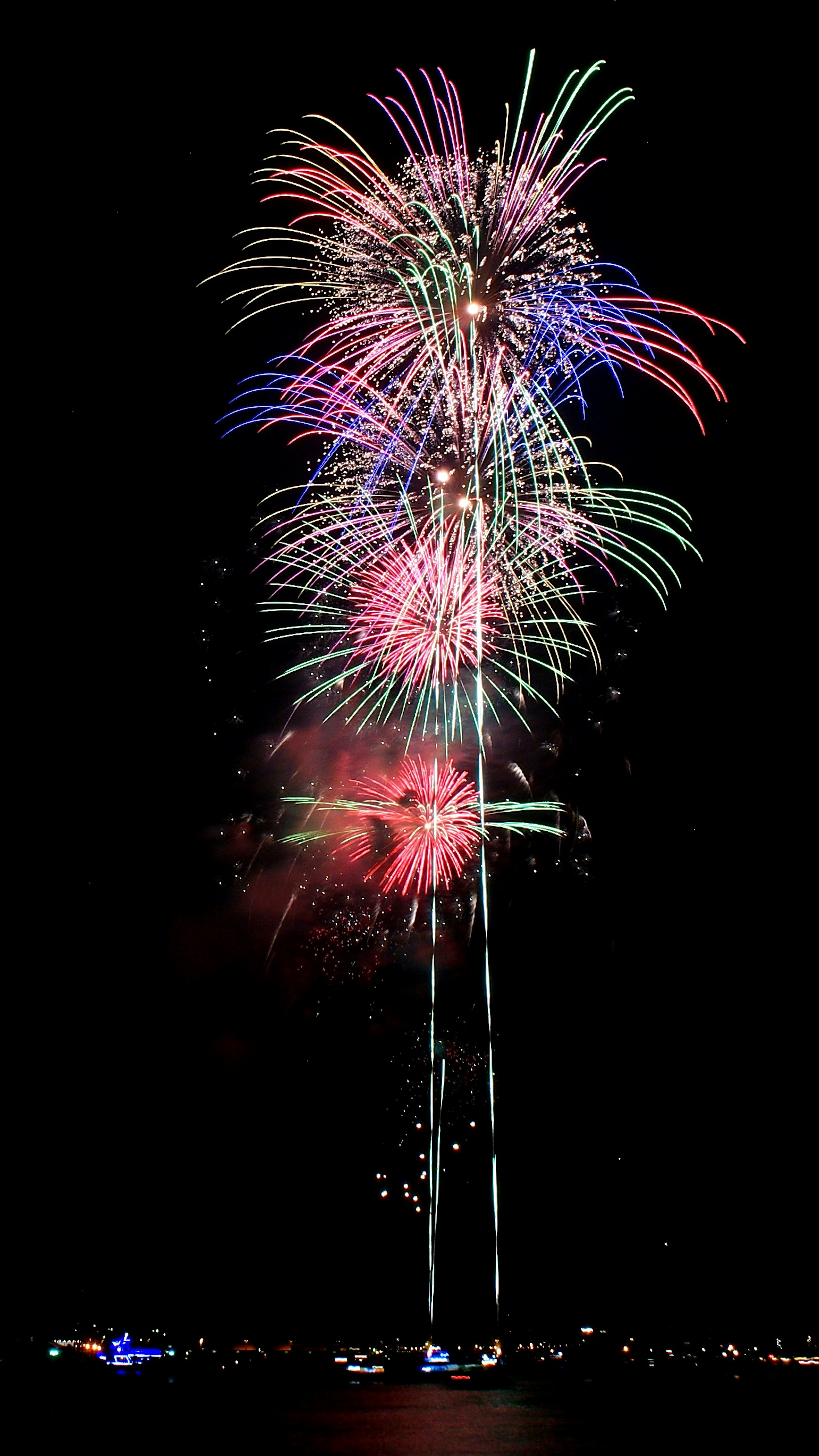 Spettacolo di fuochi d'artificio colorati nel cielo notturno con esplosioni rosse, blu e bianche