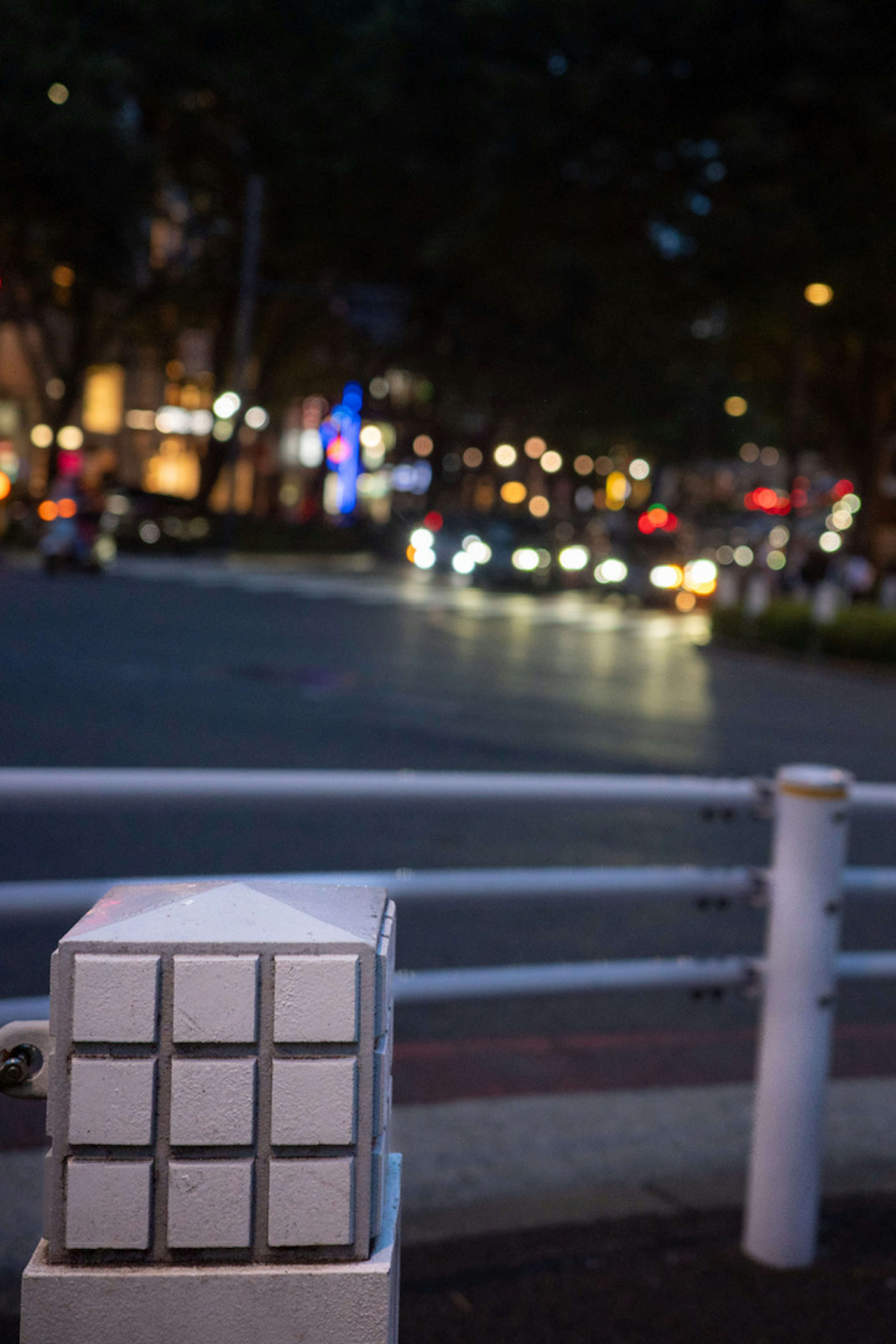 夜の街角の白いボックスとぼやけた車のライト