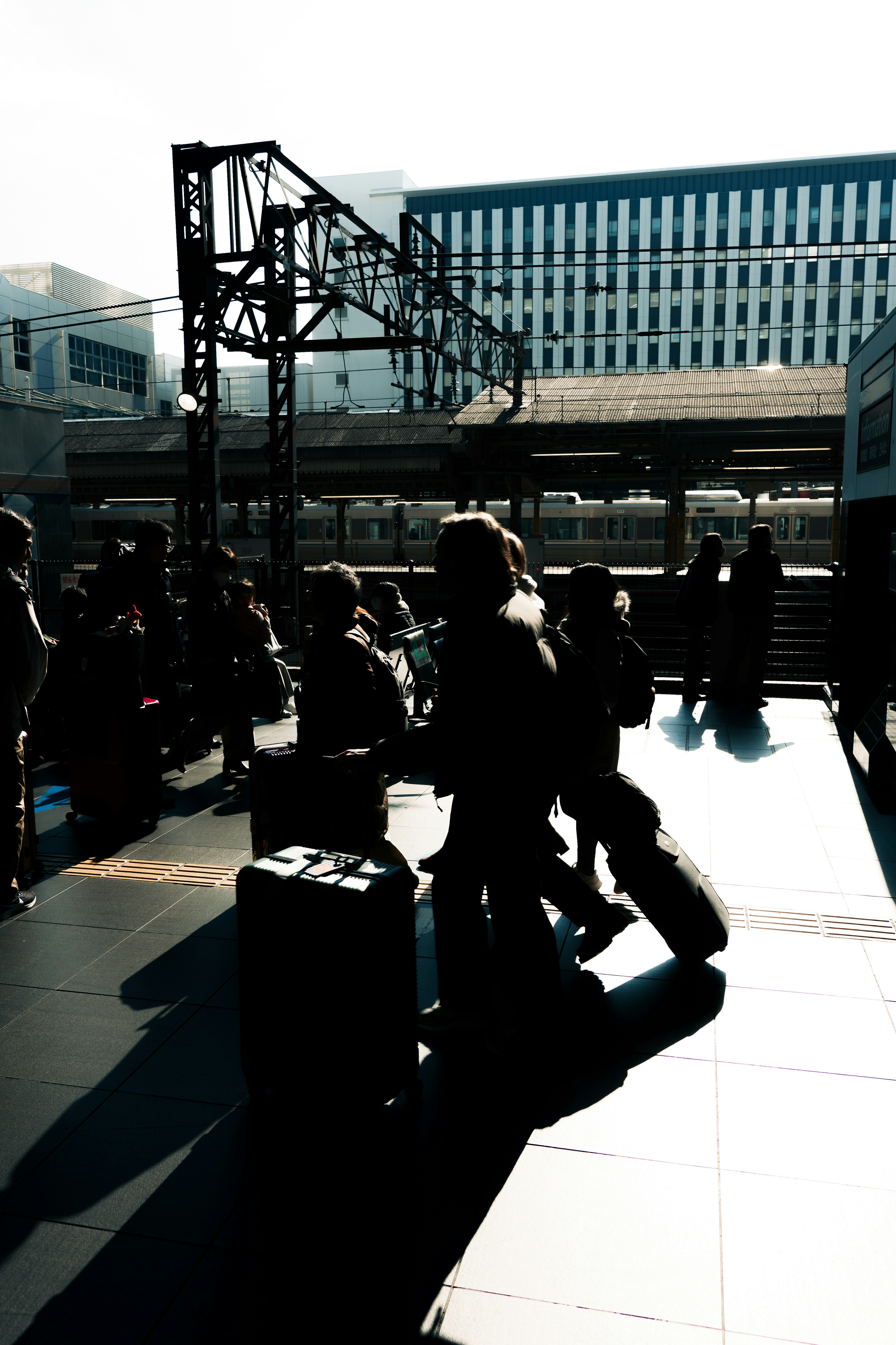 Silhouettes of travelers with luggage at a train station platform