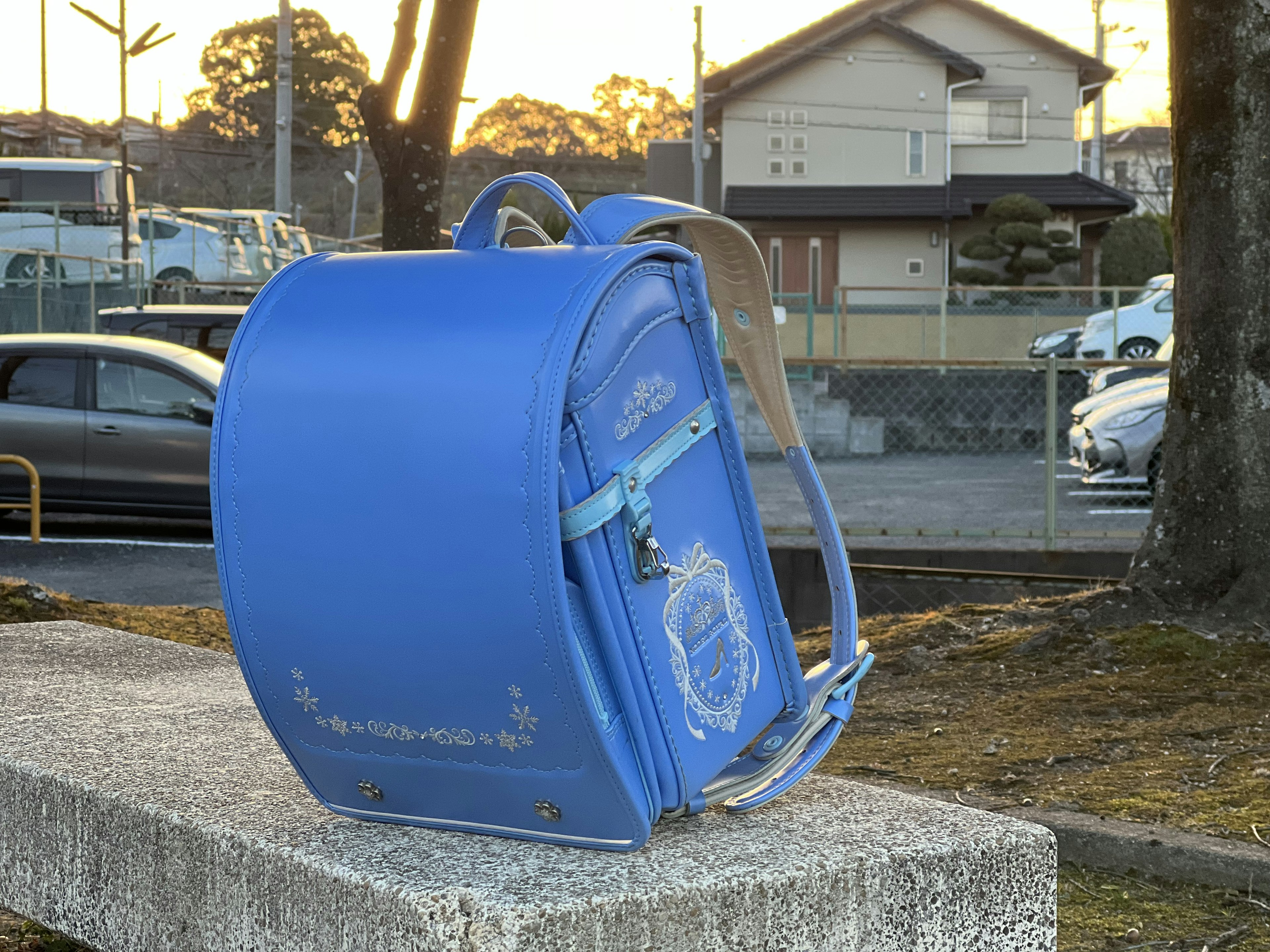 A blue randoseru sits on a concrete surface during sunset