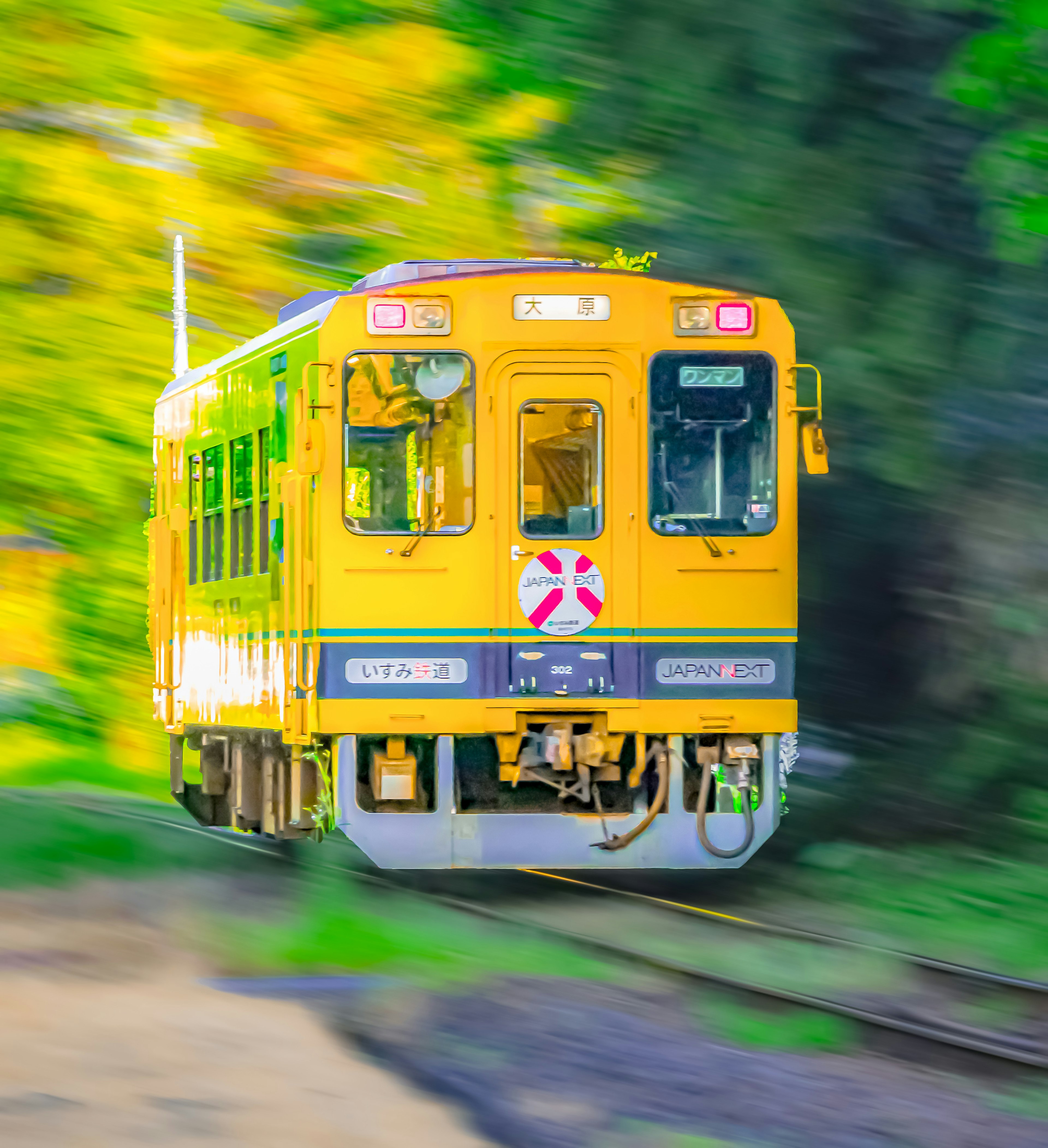 Kereta kuning bergerak melalui lanskap hijau