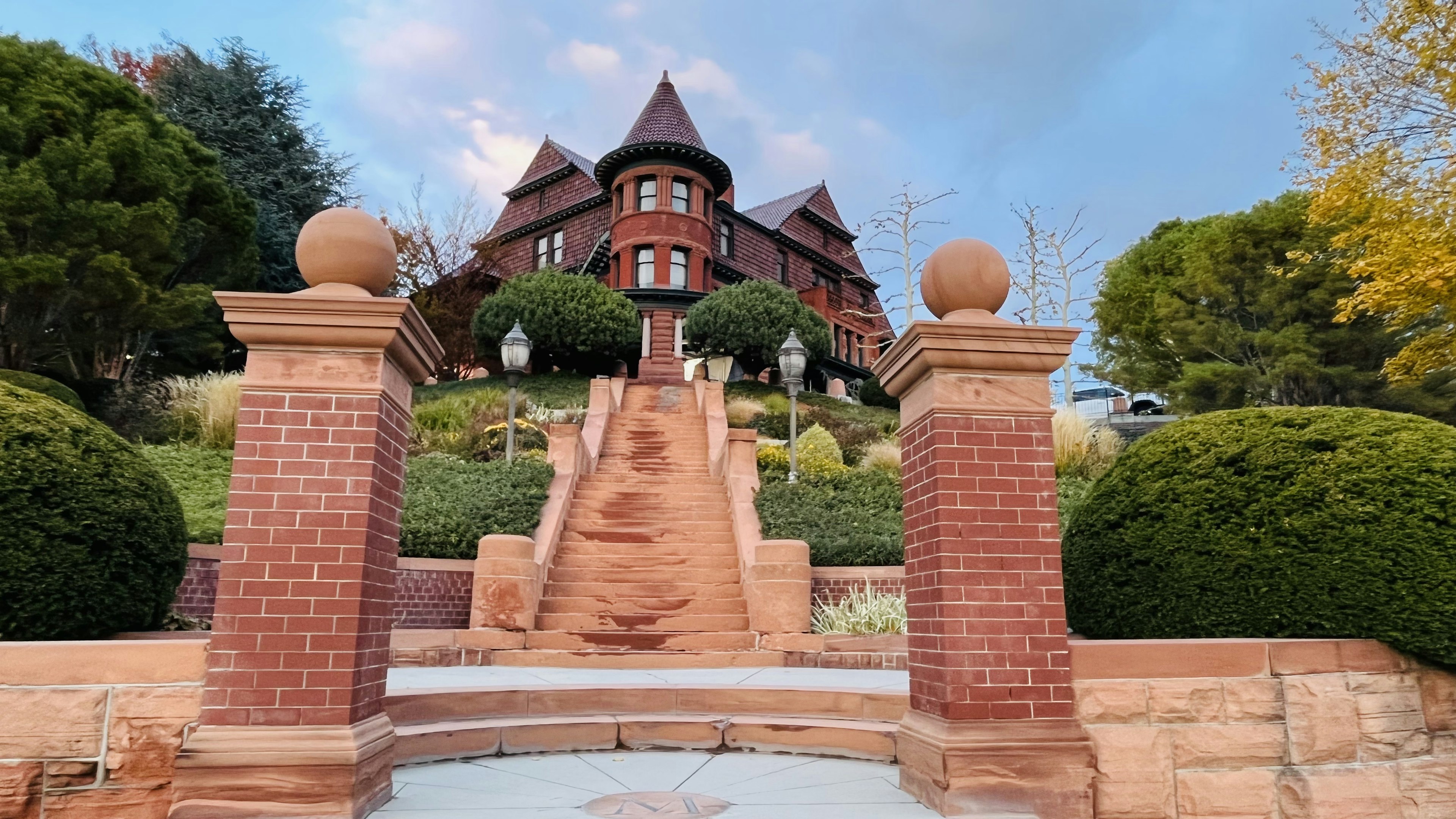 Magnifique escalier menant à une grande maison en briques rouges avec des jardins verts